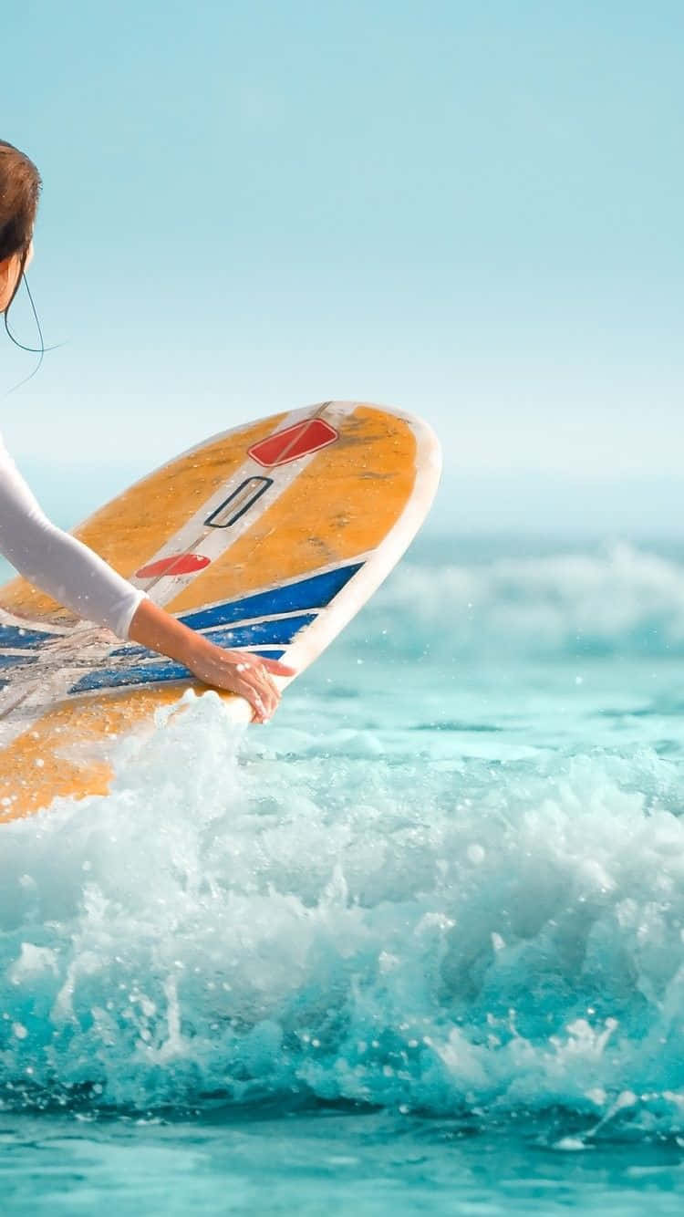 Surfing iPhone 桌布 壁紙 — 一名衝浪手抓住色彩繽紛的衝浪板，在清澈的藍天下，碧綠色的海浪在他們腳下翻湧。