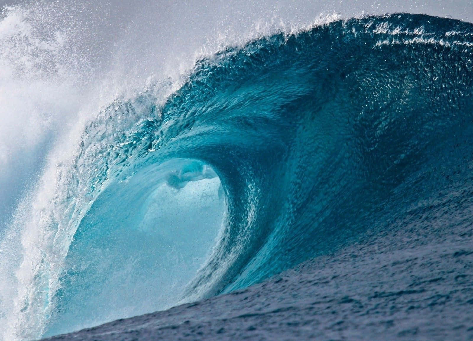 waves 桌布 壁紙 — 一名衝浪者在巨大的藍綠色海浪中衝浪，形成一個完美的桶狀浪，帶有白色浪花。