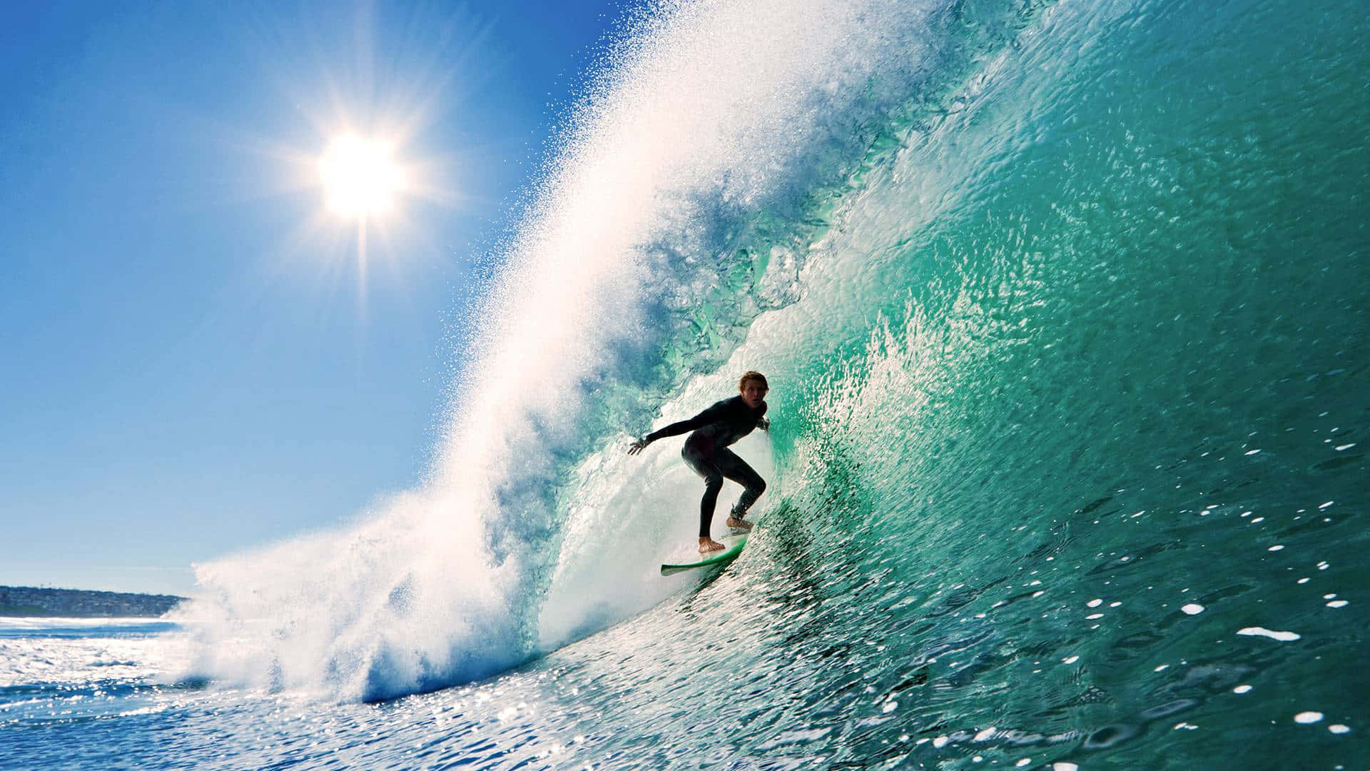 surfing 桌布 壁紙 — 一名衝浪者在烈日當空、萬里無雲的藍天下，駕馭著巨大的藍綠色海浪。