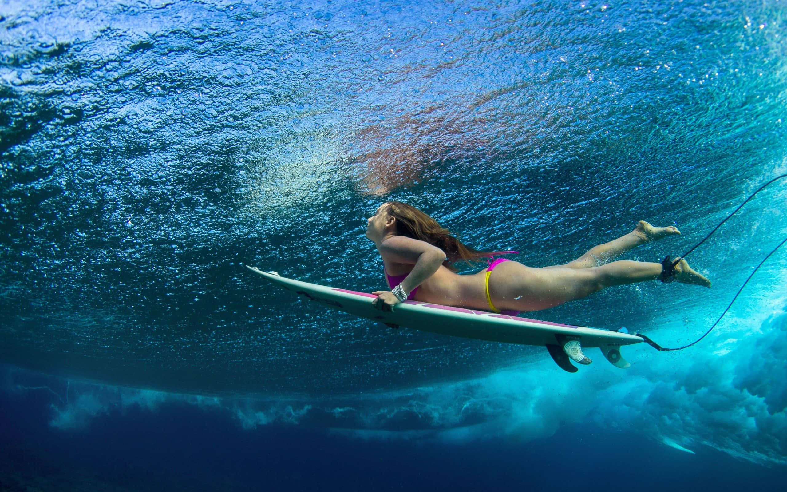 Beach Water Sports 桌布 壁紙 — 一名衝浪者在破碎的波浪下於水中滑行，陽光透過碧綠的海洋照射下來。