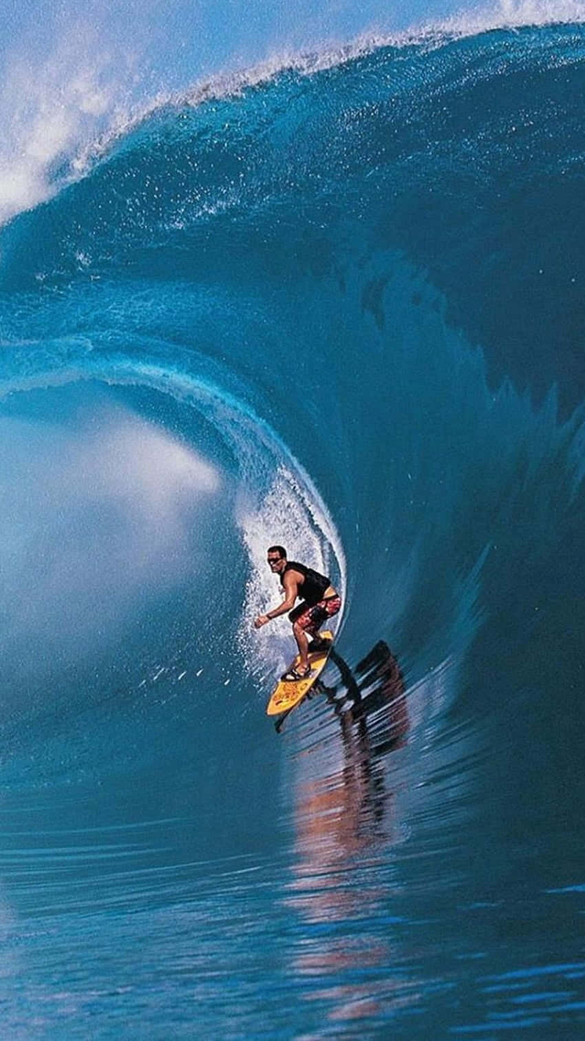 Surfing iPhone 桌布 壁紙 — 一名衝浪者騎著一道巨大的藍綠色海浪，在完美的浪管中，周圍水花四濺。