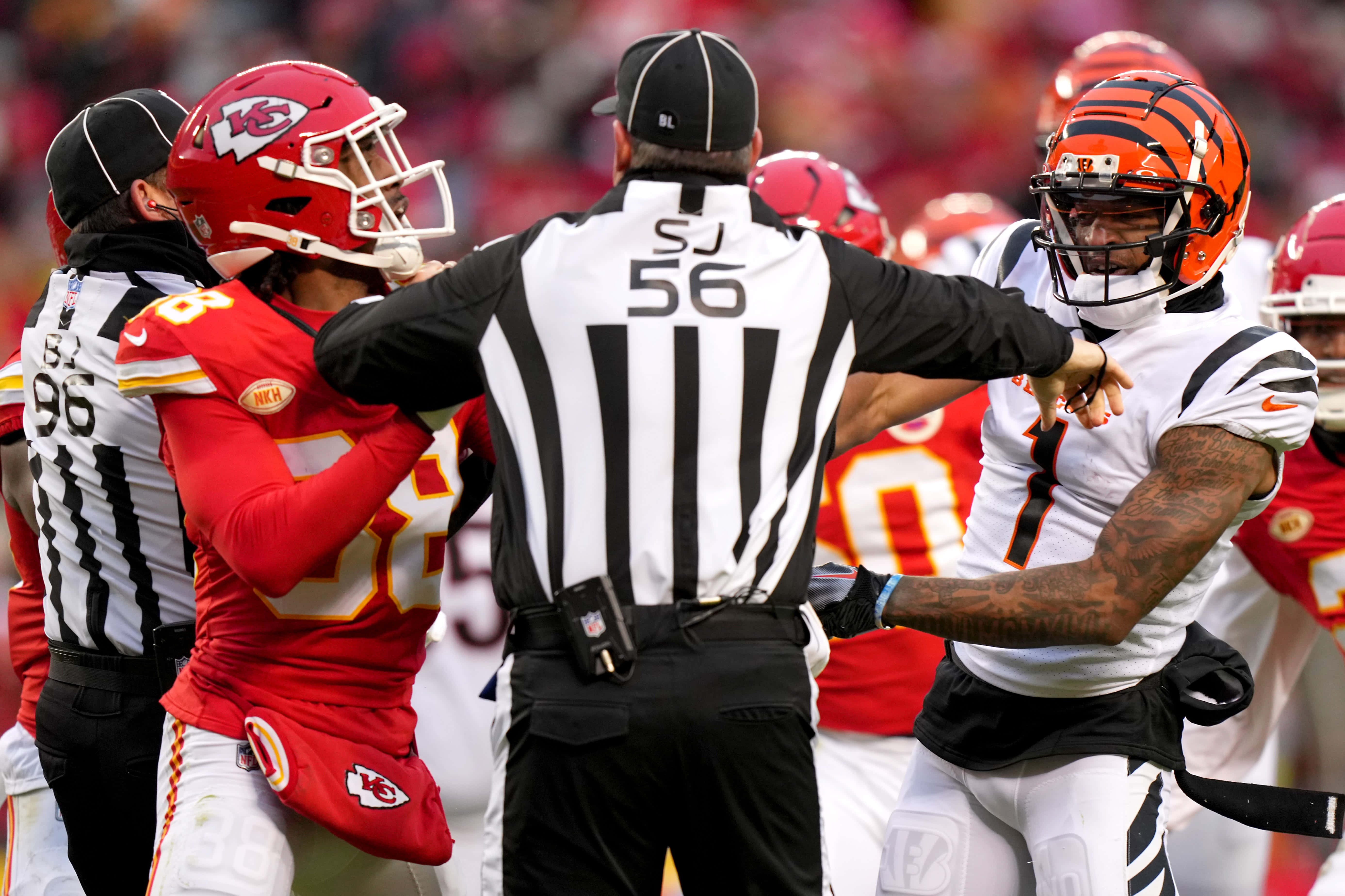 Ja'marr Chase 桌布 壁紙 — 一名裁判在比賽中將兩名NFL球員分開，場面激烈，一人穿紅色球衣，另一人穿白色球衣，兩人都戴著頭盔
