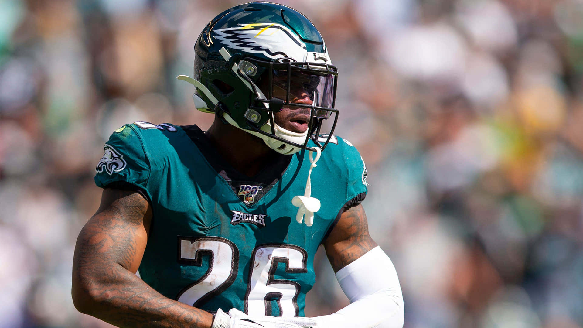 Miles Sanders 桌布 壁紙 — 一名費城老鷹隊美式足球員身穿青綠色26號球衣，在日間比賽中專注地奔跑。
