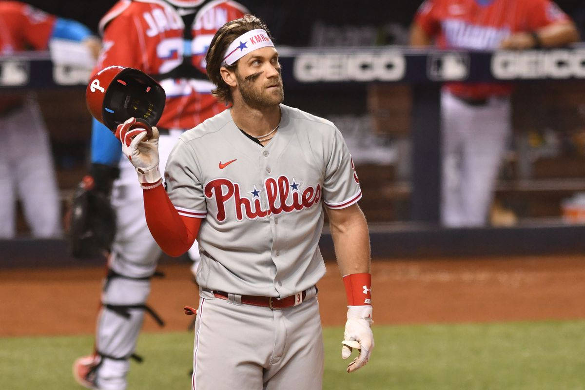 Phillies 桌布 壁紙 — 一名費城費城人棒球運動員在夜間手持頭盔，帶著專注的表情離開球場。
