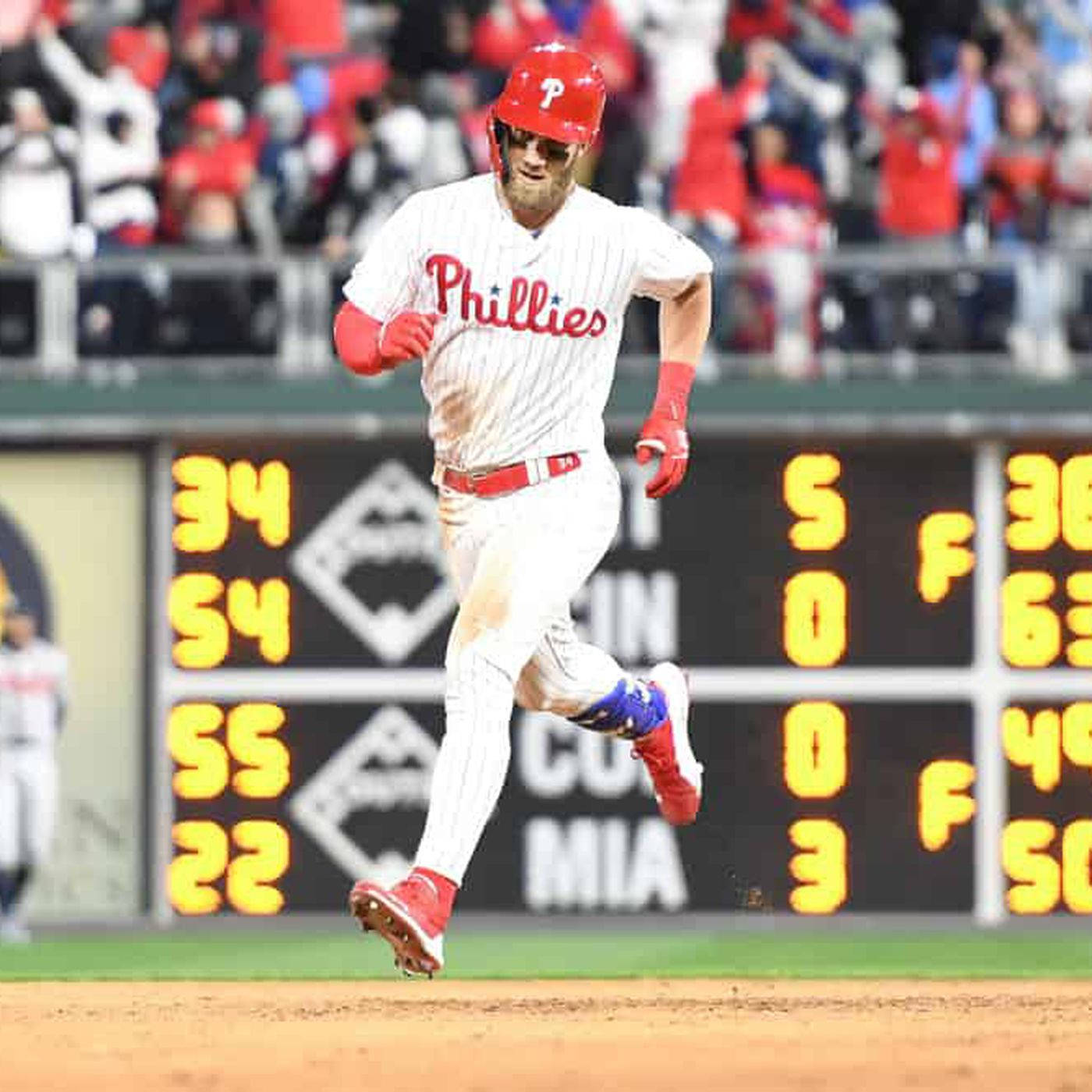 Phillies 桌布 壁紙 — 一名費城費城人棒球運動員在夜間比賽中，在身後發光的記分板襯托下，衝過泥土內野。