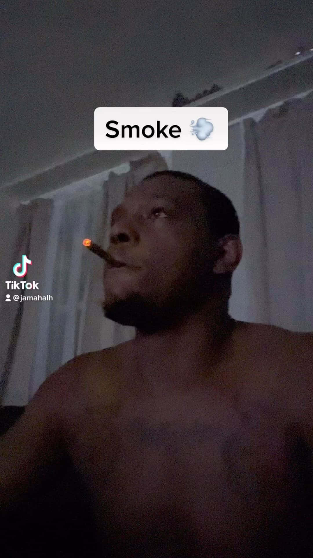 Smoking 桌布 壁紙 — 一名赤裸上身的男子在室內抽著點燃的雪茄煙，煙頭發出微弱的火光，背景是昏暗的燈光和白色窗簾。