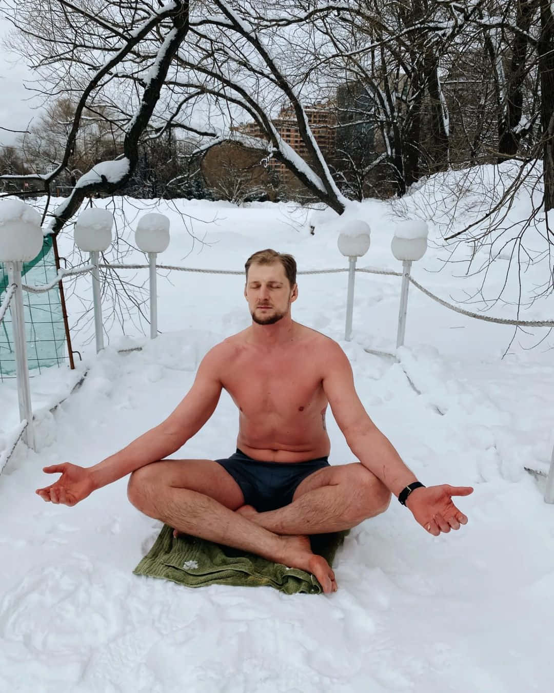 Athlete 桌布 壁紙 — 一名赤裸上身的男子在雪地中盤腿冥想，周圍是光禿的冬日樹木和白色燈籠。