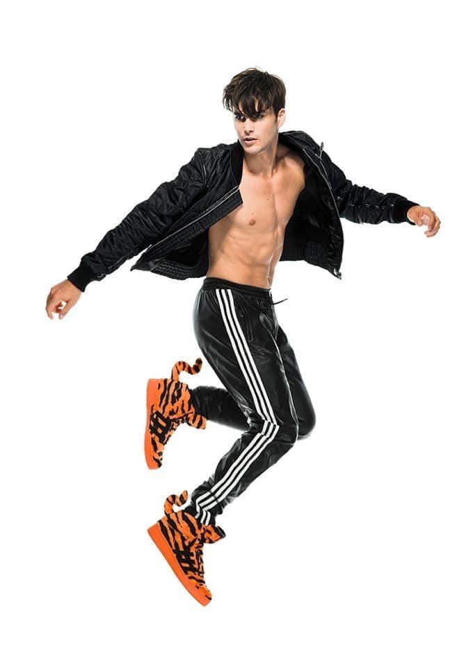 jump 桌布 壁紙 — 一名赤裸上身的男子穿著黑色運動服和橙色老虎印花運動鞋，在純白色背景上動態跳躍。
