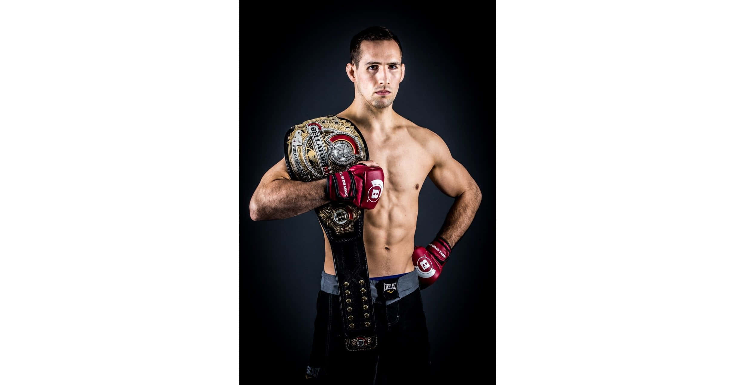 MMA 桌布 壁紙 — 一名赤裸上身的男拳擊手戴著紅色拳套，在黑暗的工作室背景下舉起冠軍腰帶。