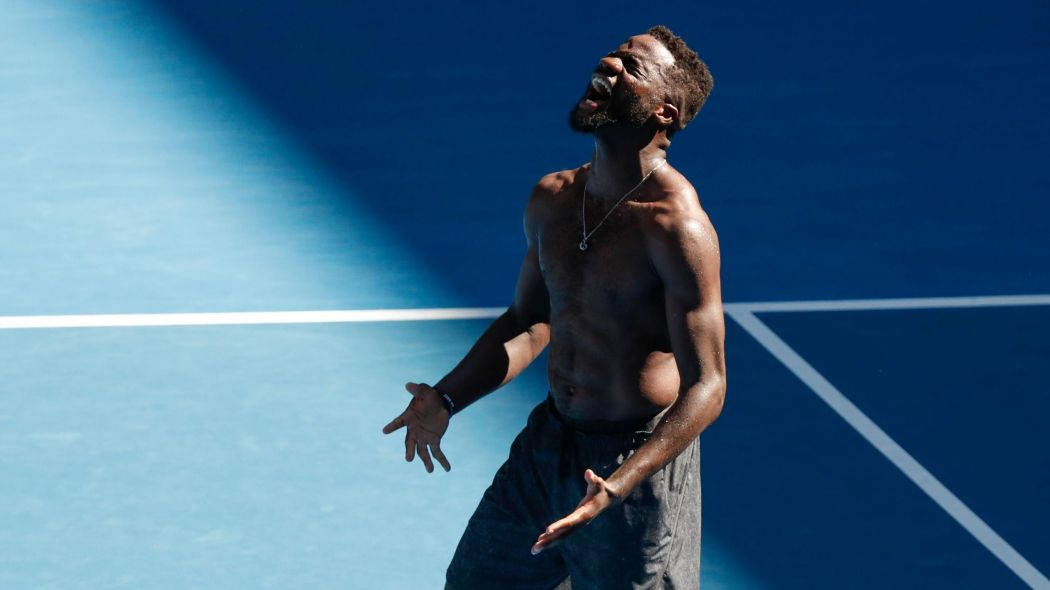 Athletic 桌布 壁紙 — 一名赤裸上身的網球運動員在明亮的陽光下，於充滿活力的藍色球場上勝利慶祝。