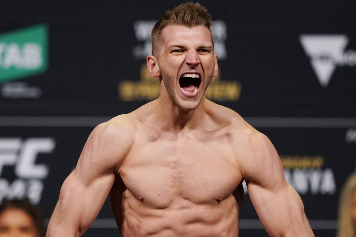 UFC 桌布 壁紙 — 一名赤裸上身的肌肉拳手在明亮的場館燈光下，於UFC賽事中激情咆哮。