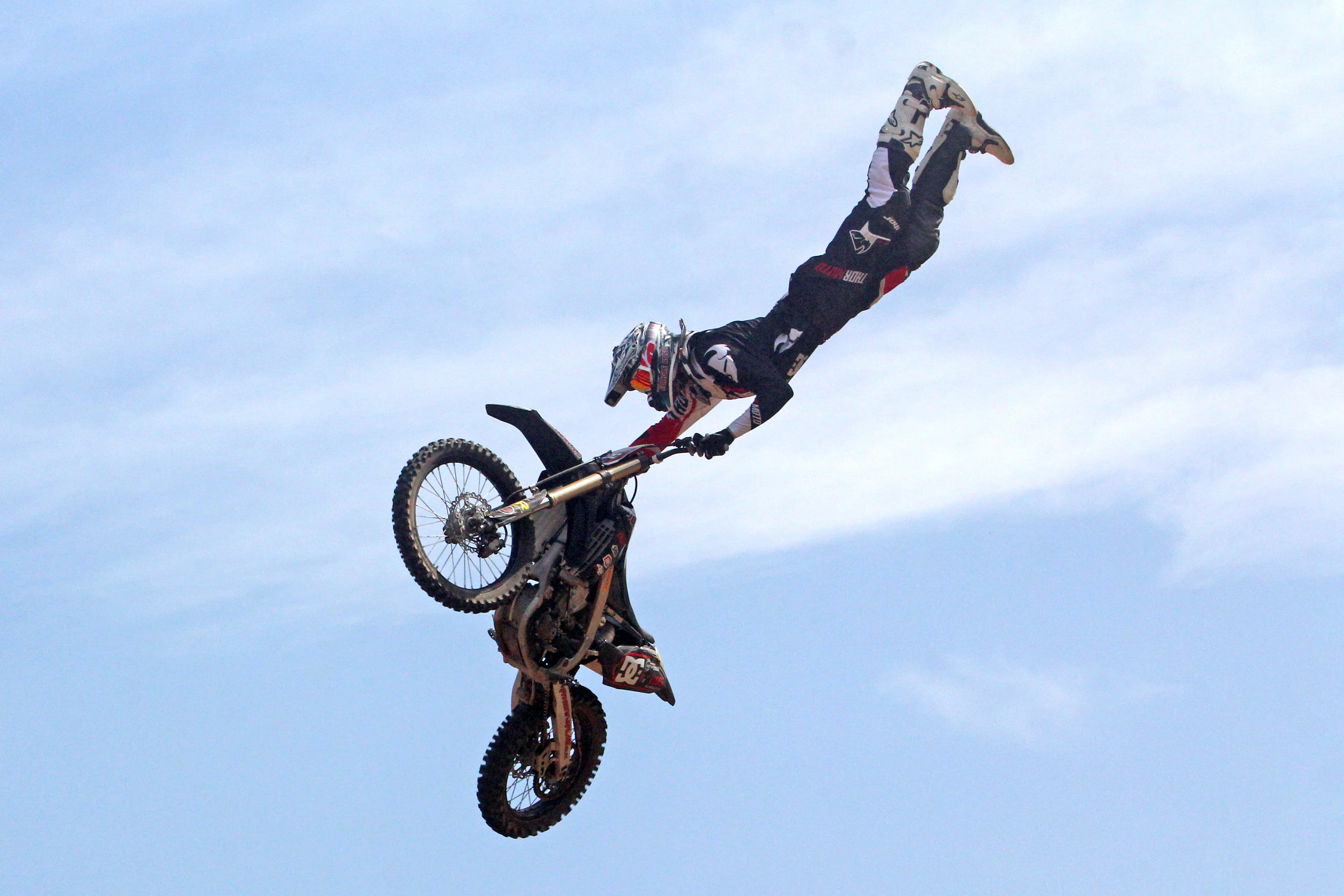 Dirtbike 桌布 壁紙 — 一名越野摩托車手在藍天白雲下表演倒轉空中特技。