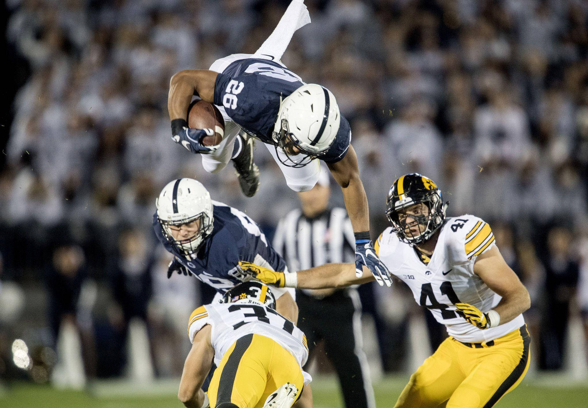 Saquon Barkley 桌布 壁紙 — 一名足球員在球場燈光下躍起接球，防守球員逼近。