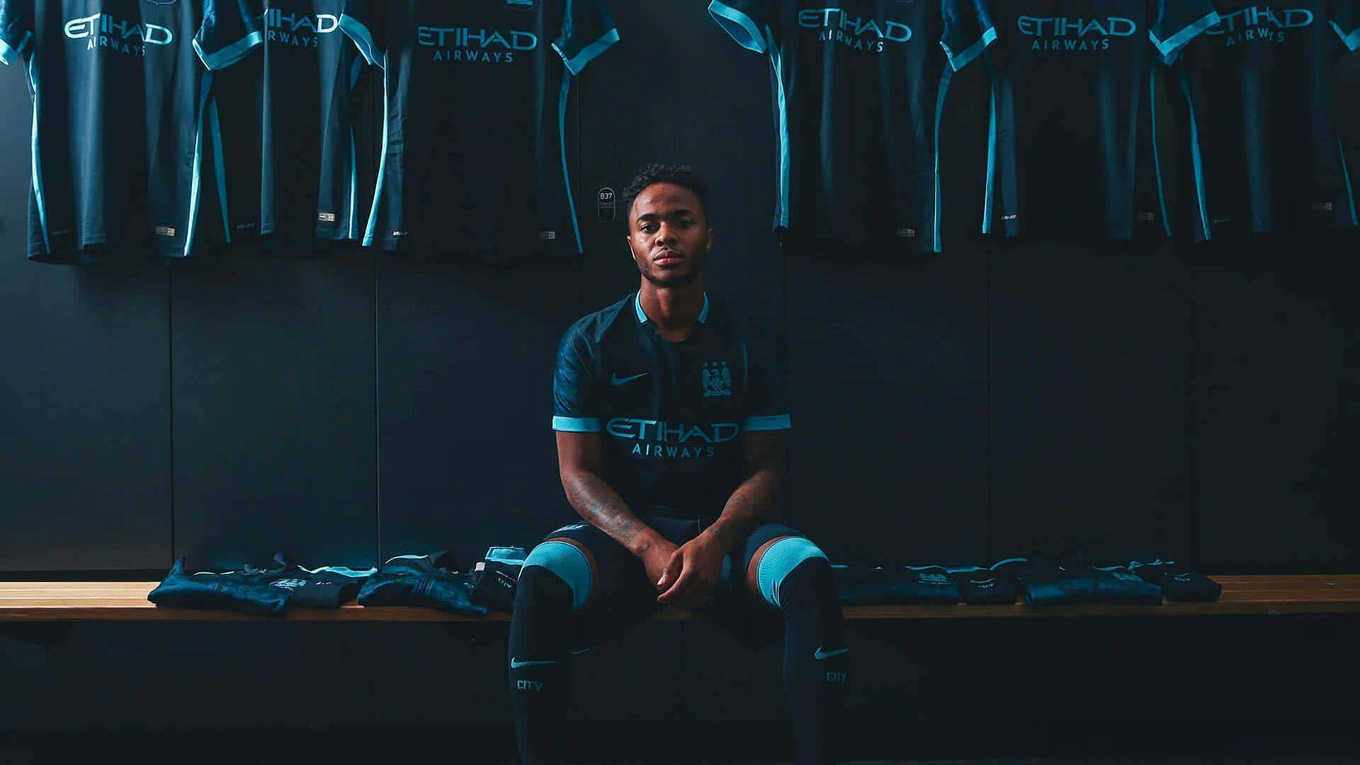 Sterling 桌布 壁紙 — 一名足球運動員莊嚴地坐在光線昏暗的更衣室長椅上，周圍掛著球隊球衣。