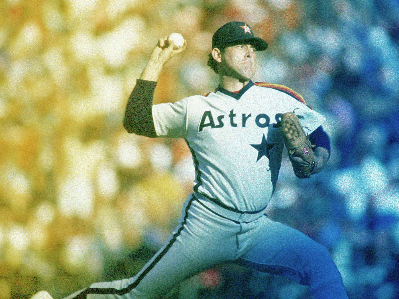 Nolan Ryan 桌布 壁紙 — 一名身穿 Astros 球衣的棒球投手正在投球，背景是模糊的球場人群。