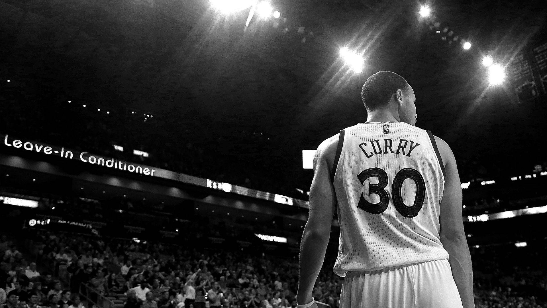 Curry 桌布 壁紙 — 一名身穿30號球衣的籃球運動員獨自站在球場上，背景是明亮的場館燈光和人群。