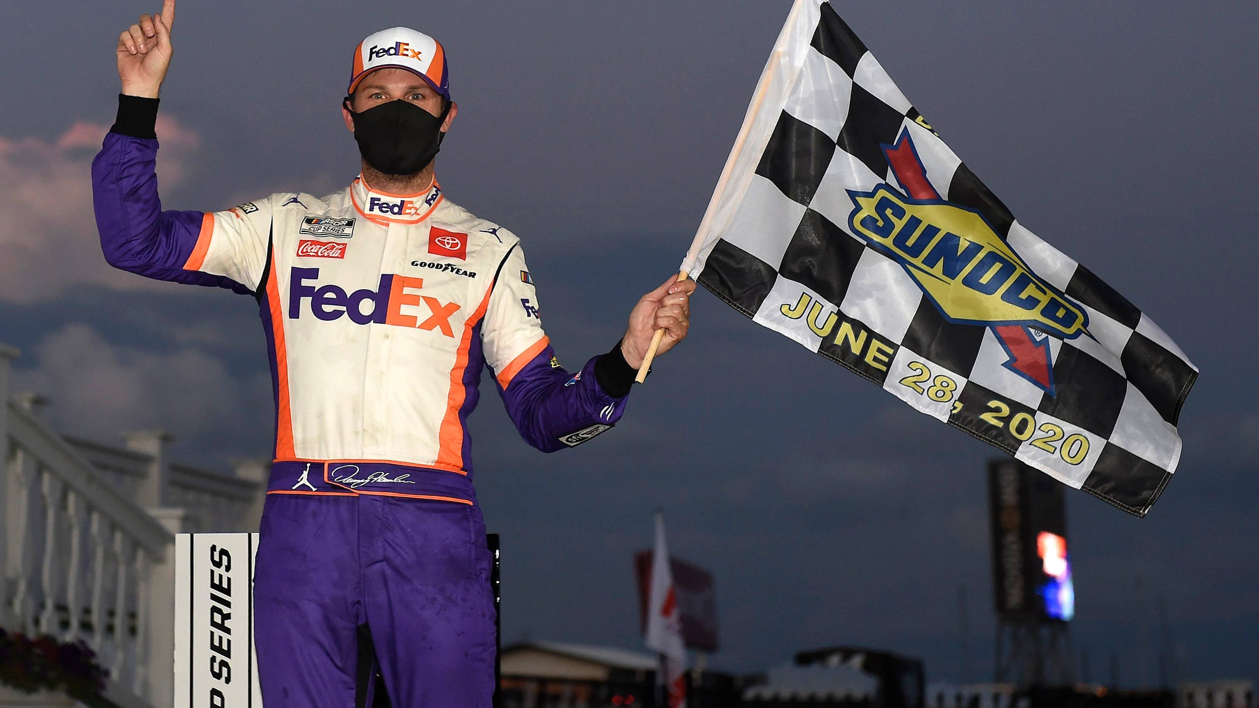 Denny Hamlin 桌布 壁紙 — 一名身穿FedEx賽車服的NASCAR車手在2020年6月28日黃昏贏得比賽後揮舞方格旗。