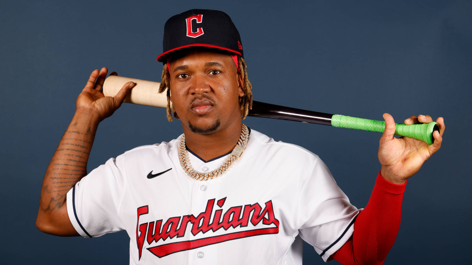 Jose Ramirez 桌布 壁紙 — 一名身穿Guardians球衣的棒球選手在深藍色攝影棚背景下將球棒扛在肩上。