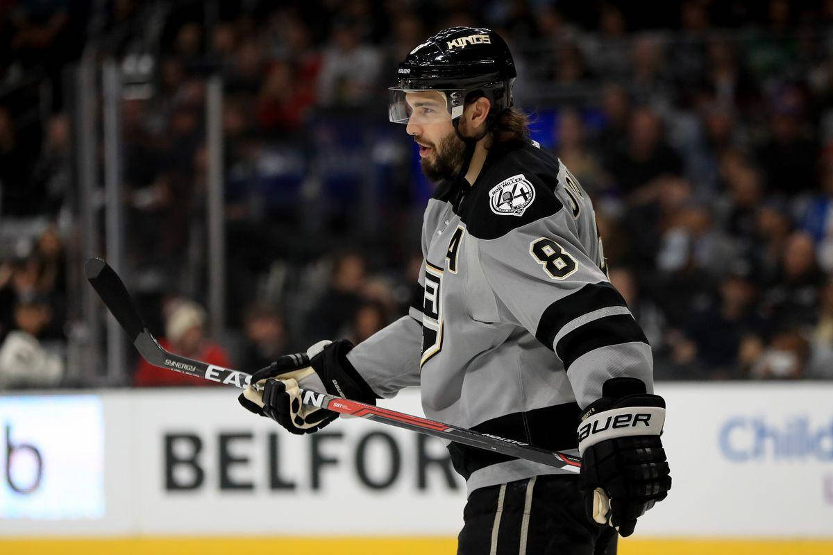 hockey 桌布 壁紙 — 一名身穿Kings球衣的曲棍球運動員在比賽中專注地握著球棍，場館燈光下充滿強度。
