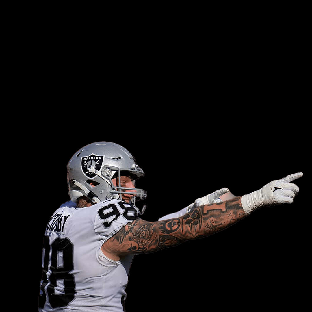 tattoos 桌布 壁紙 — 一名身穿Raiders球衣的足球員在純黑背景前向前指，手臂上可見刺青。