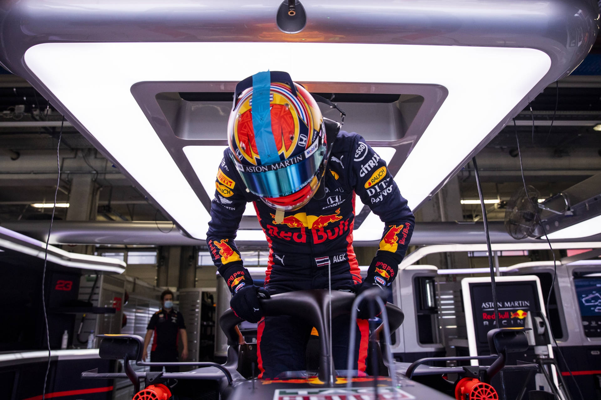 身穿賽車裝備的F1車手坐在車庫內的賽車中。 — 紅牛F1 壁紙