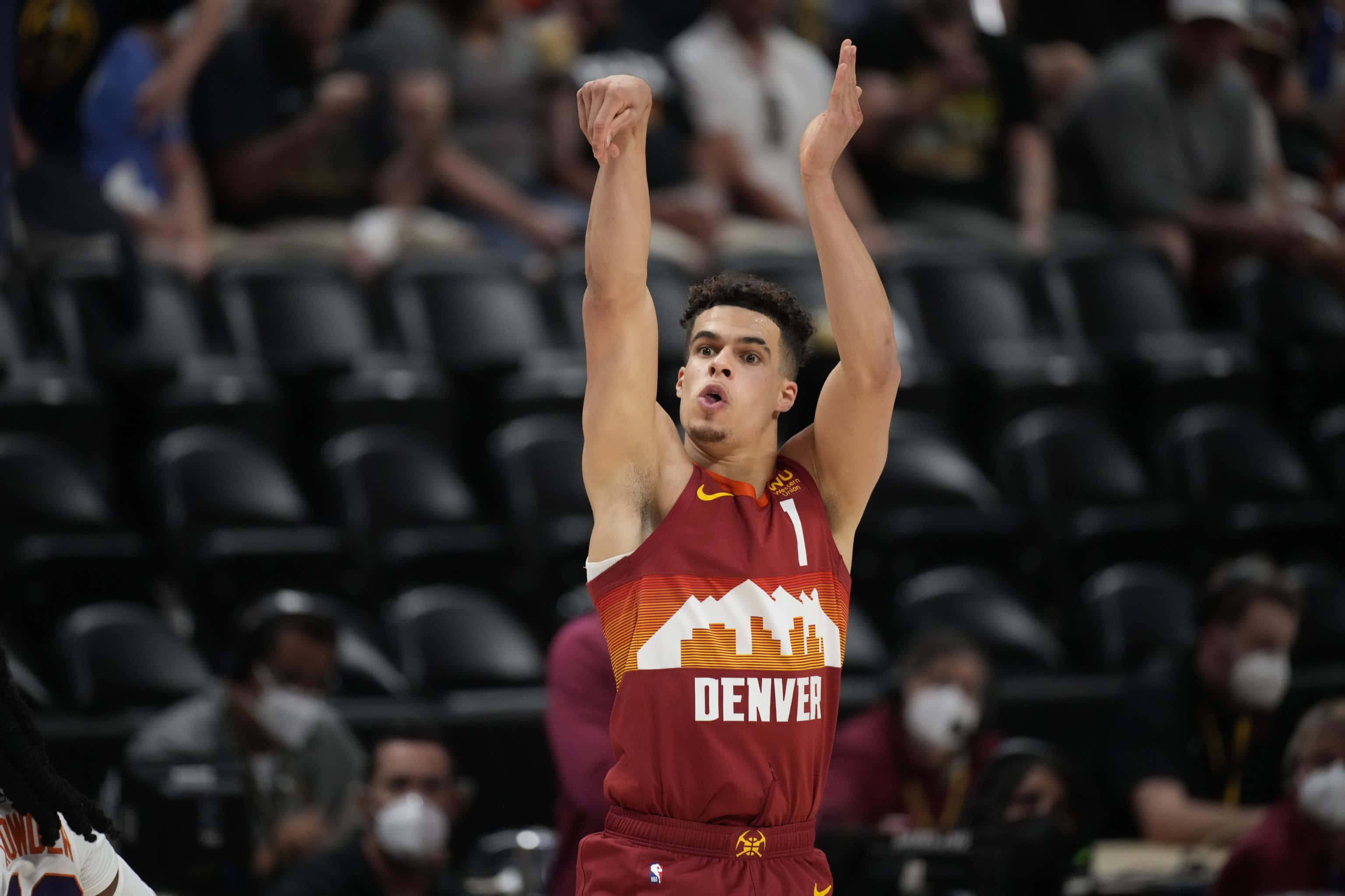 NBA 桌布 壁紙 — 一名身穿丹佛球衣的籃球運動員在擠滿觀眾的場館中比賽時舉起拳頭慶祝。