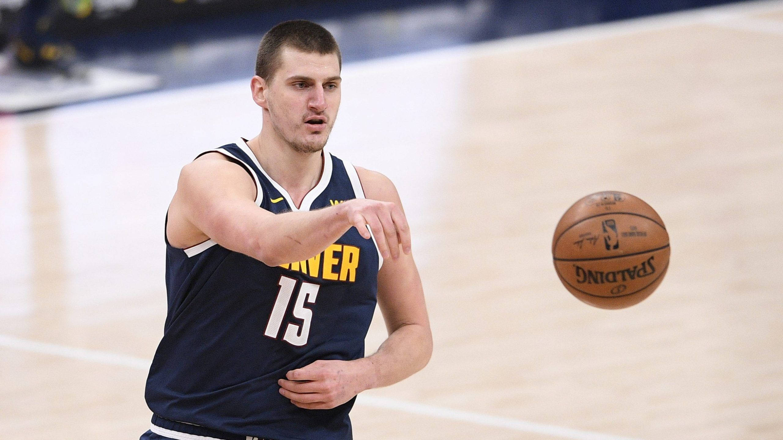 Jokic 桌布 壁紙 — 一名身穿丹佛球衣的籃球運動員準備在拋光球場上傳球 Spalding 球。