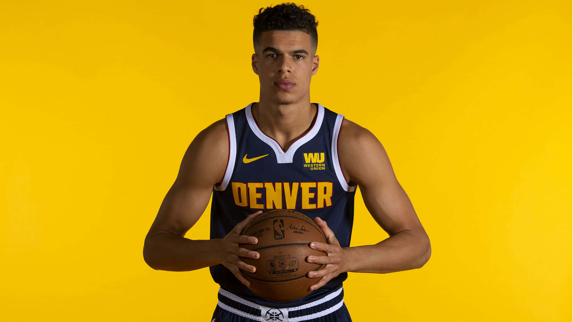 丹佛金塊籃球運動員在黃色工作室拍攝中持球。 — NBA 壁紙