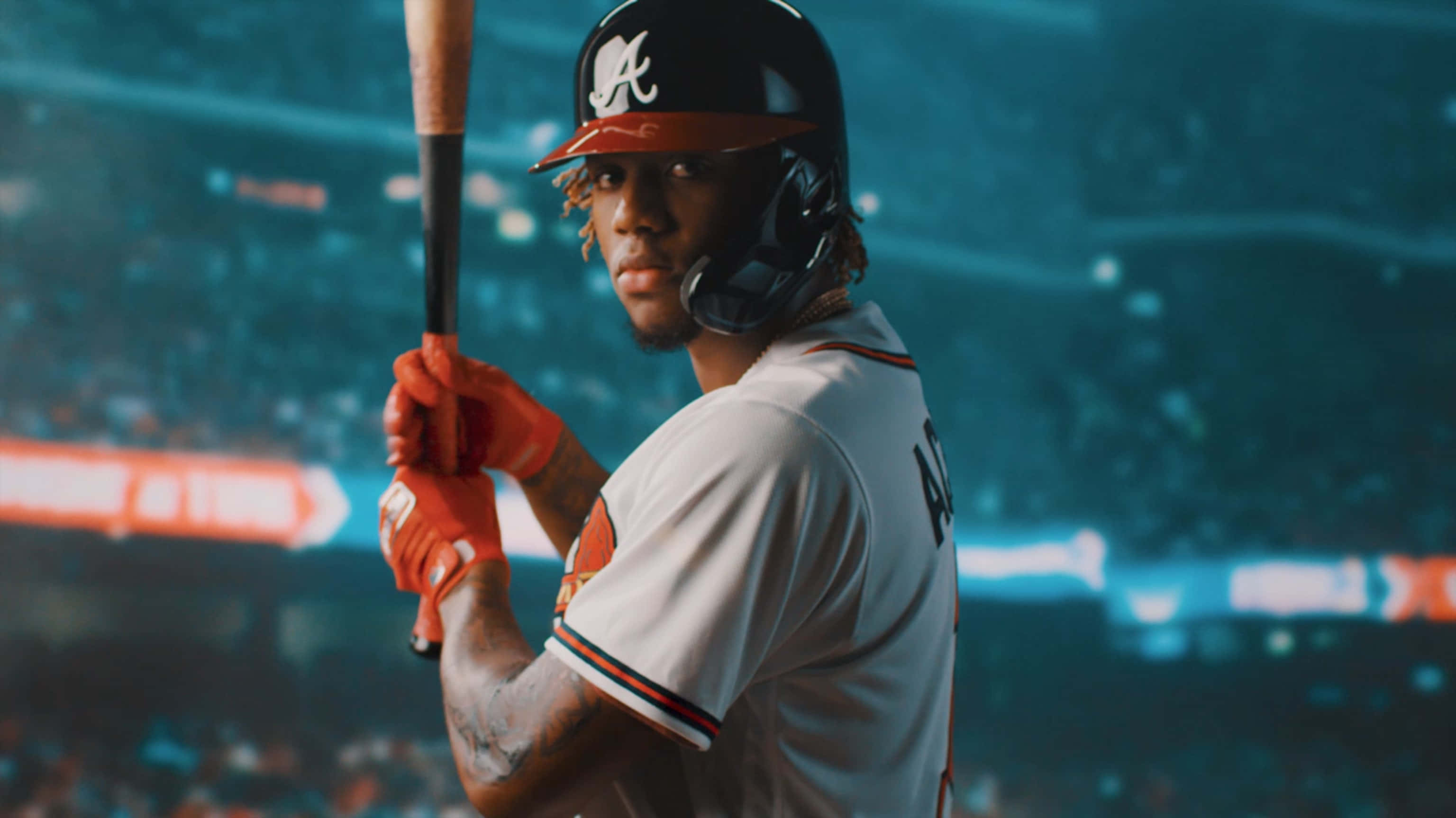 Atlanta Braves Desktop 桌布 壁紙 — 一名身穿亞特蘭大勇士隊球衣的棒球選手緊握球棒，在球場燈光下專注地凝視鏡頭。