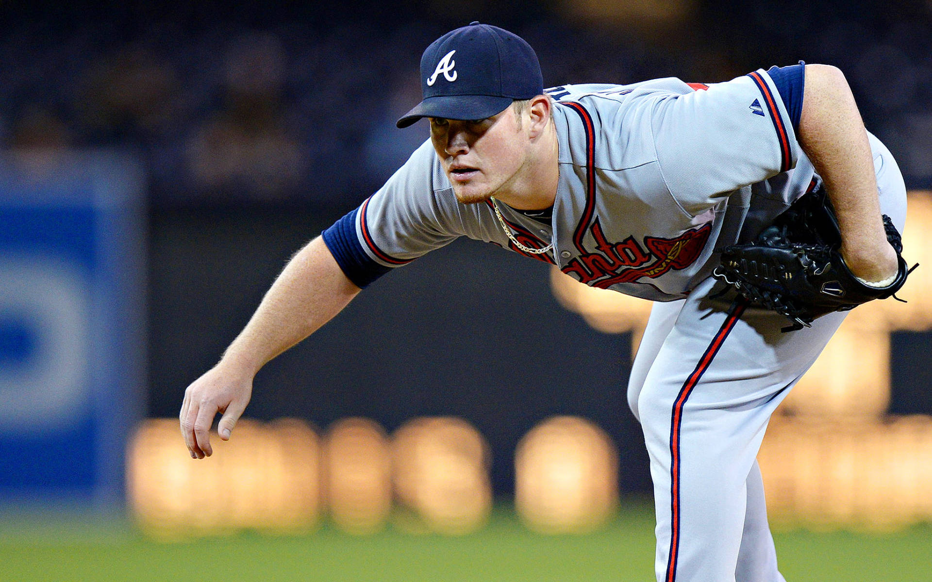 Braves 桌布 壁紙 — 一名身穿亞特蘭大勇士隊球衣的棒球投手在夜間燈光球場上投球，背景有模糊的球場燈光。