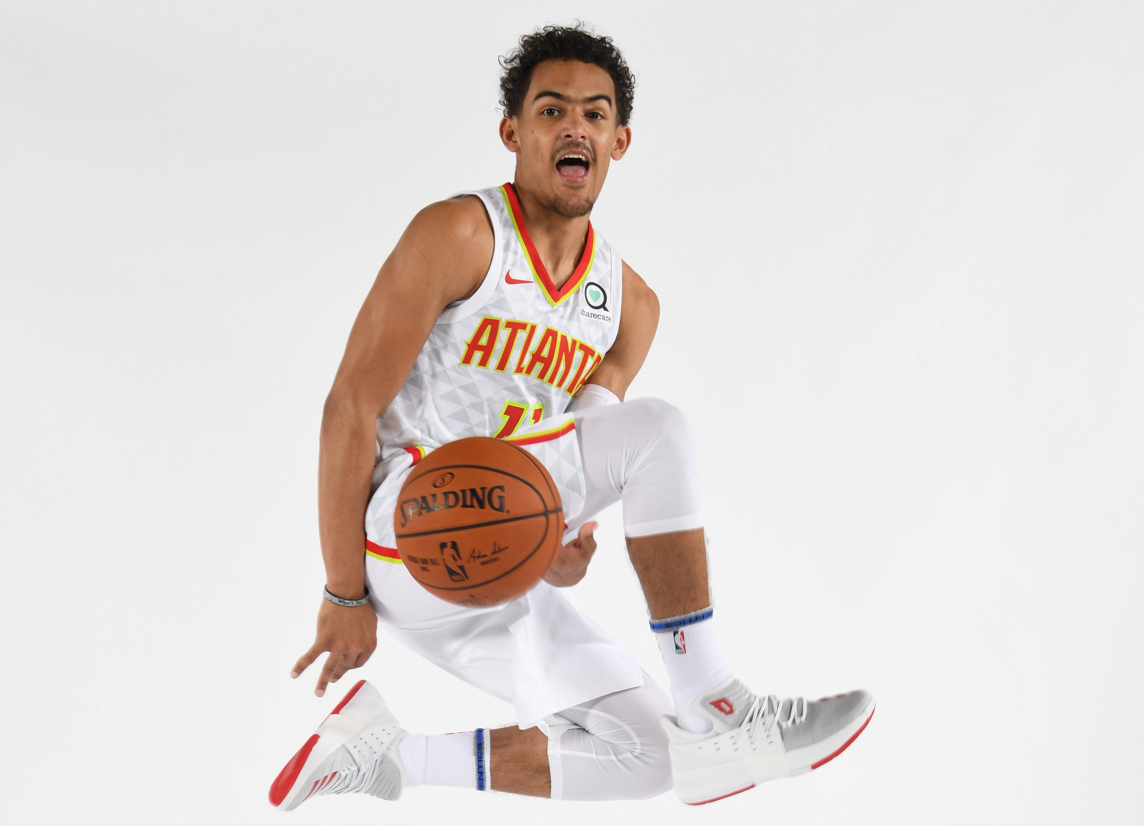 NBA 桌布 壁紙 — 一名身穿亞特蘭大球衣的動感籃球運動員在半空中蹲下，手持籃球，背景為純白色。