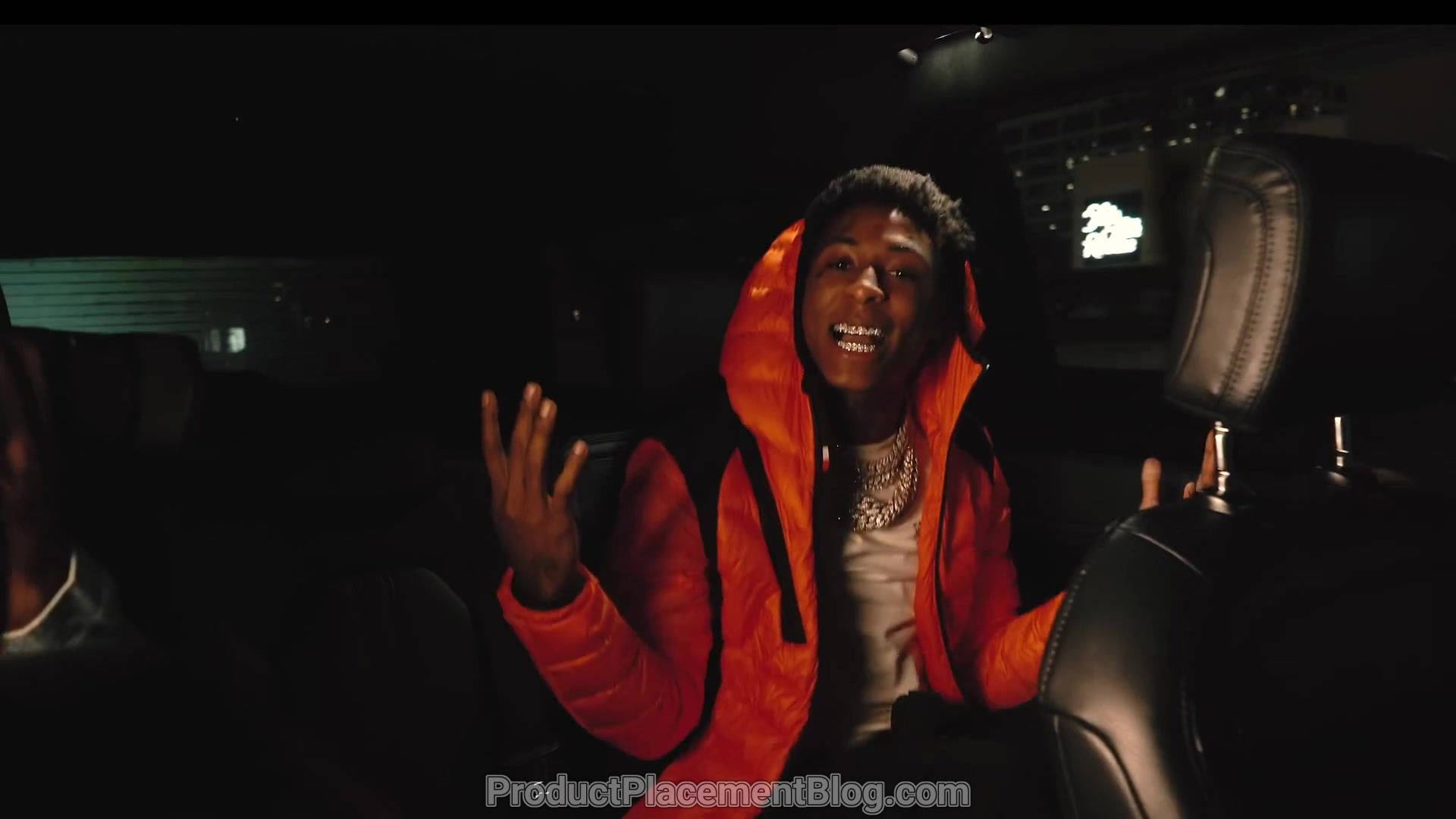  壁紙 — 一名身穿亮橙色連帽衫的年輕男子在夜間坐在一輛黑色汽車的後座，滿臉喜悅。