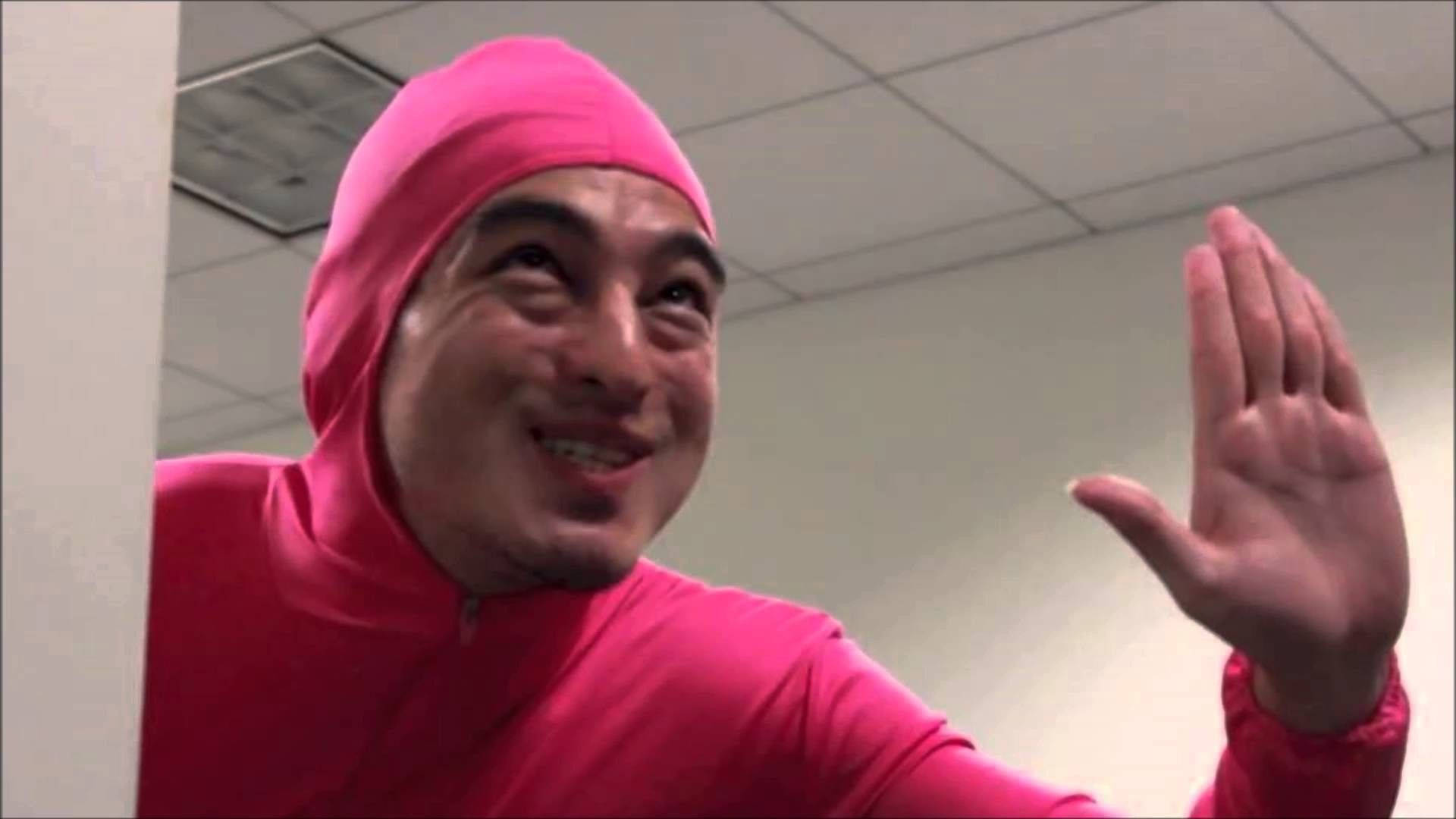 高清 桌布 壁紙 — 一名身穿亮粉紅色全身套裝的男子在辦公室角落微笑揮手。