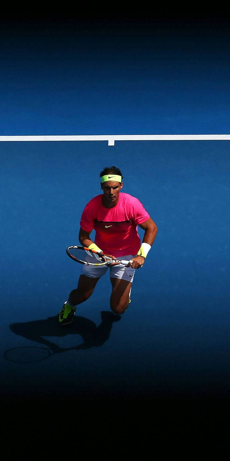 Tennis 桌布 壁紙 — 一名身穿亮粉紅色襯衫和螢光頭帶的網球運動員在深藍色球場上，在戲劇性燈光下向前猛衝。