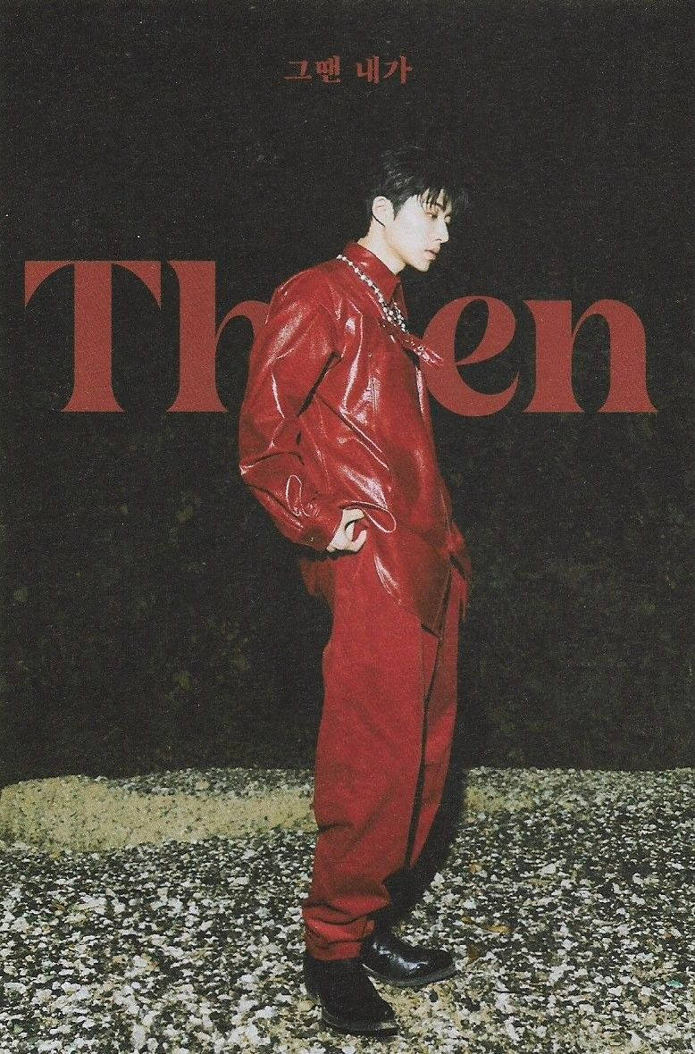 kim hanbin 桌布 壁紙 — 一名身穿亮面紅色連身褲的年輕男子自信地站在帶有粗體紅色字體的深色紋理牆壁前。