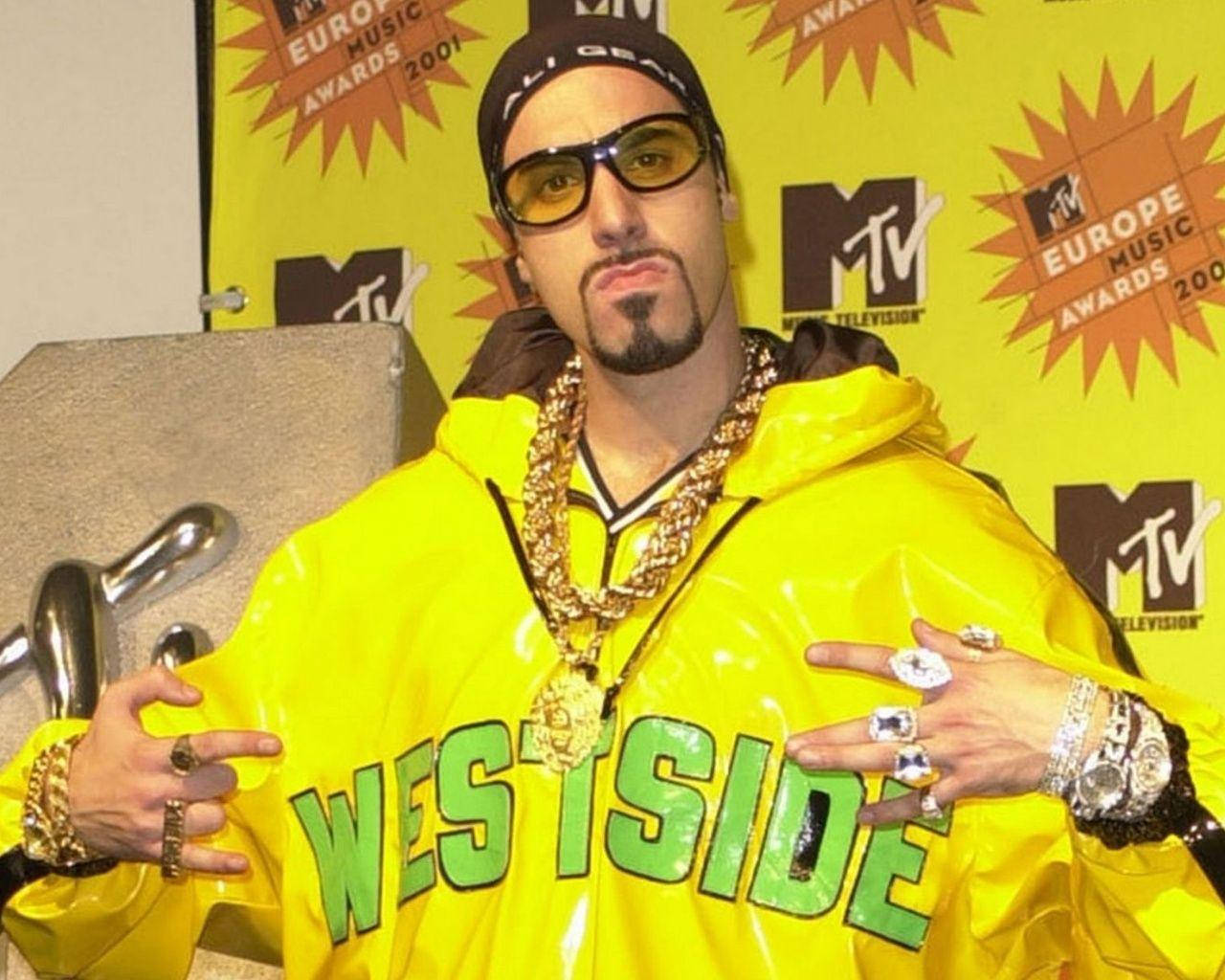 Hip Hop 桌布 壁紙 — 一名身穿亮黃色 'WESTSIDE' 連帽衫、佩戴金鏈的男子在2001年MTV歐洲音樂大獎上自信地擺姿勢。