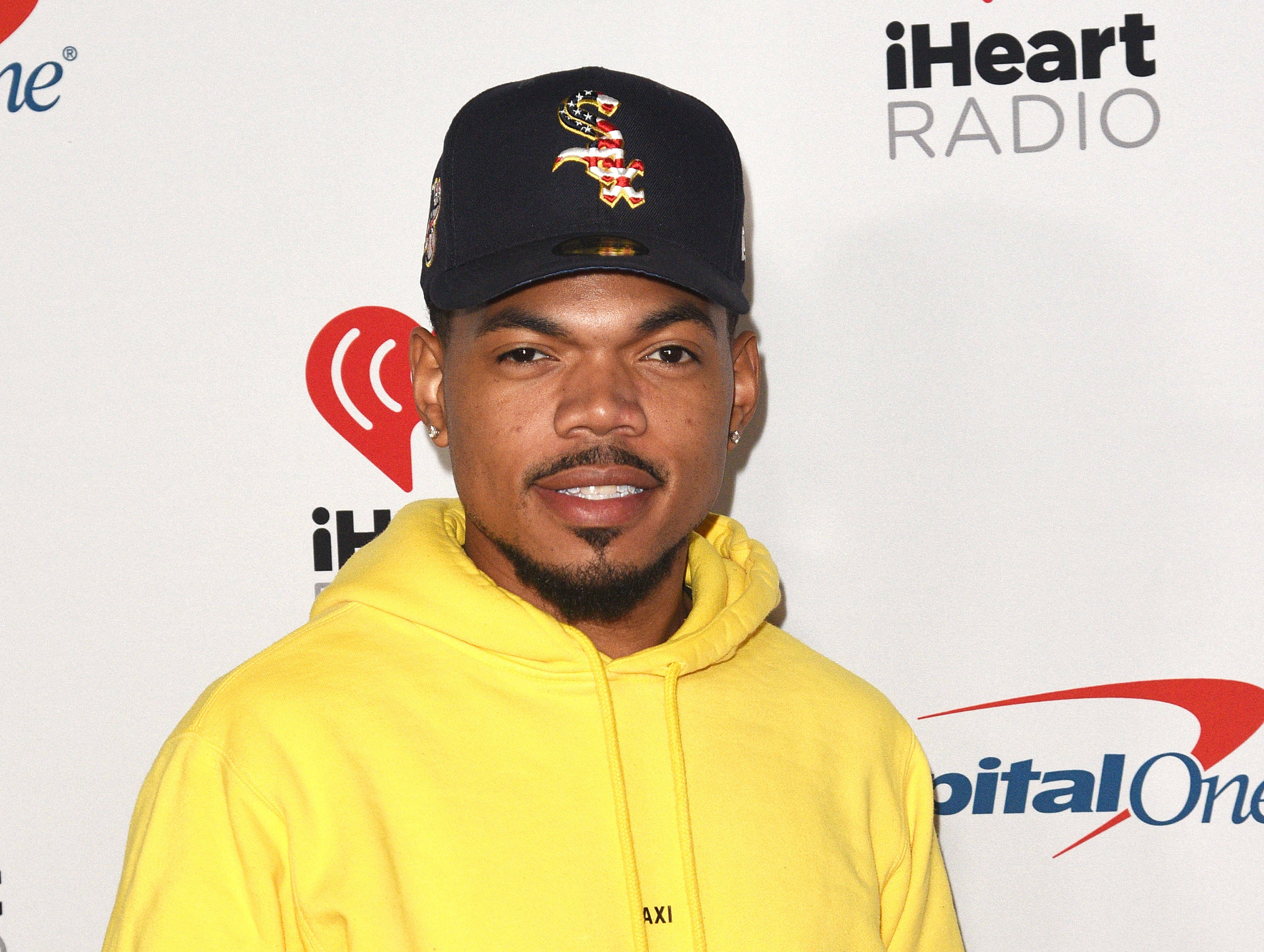 chance 桌布 壁紙 — 一名身穿亮黃色連帽衫、戴黑色帽子的男子在品牌活動背景前對著鏡頭微笑。