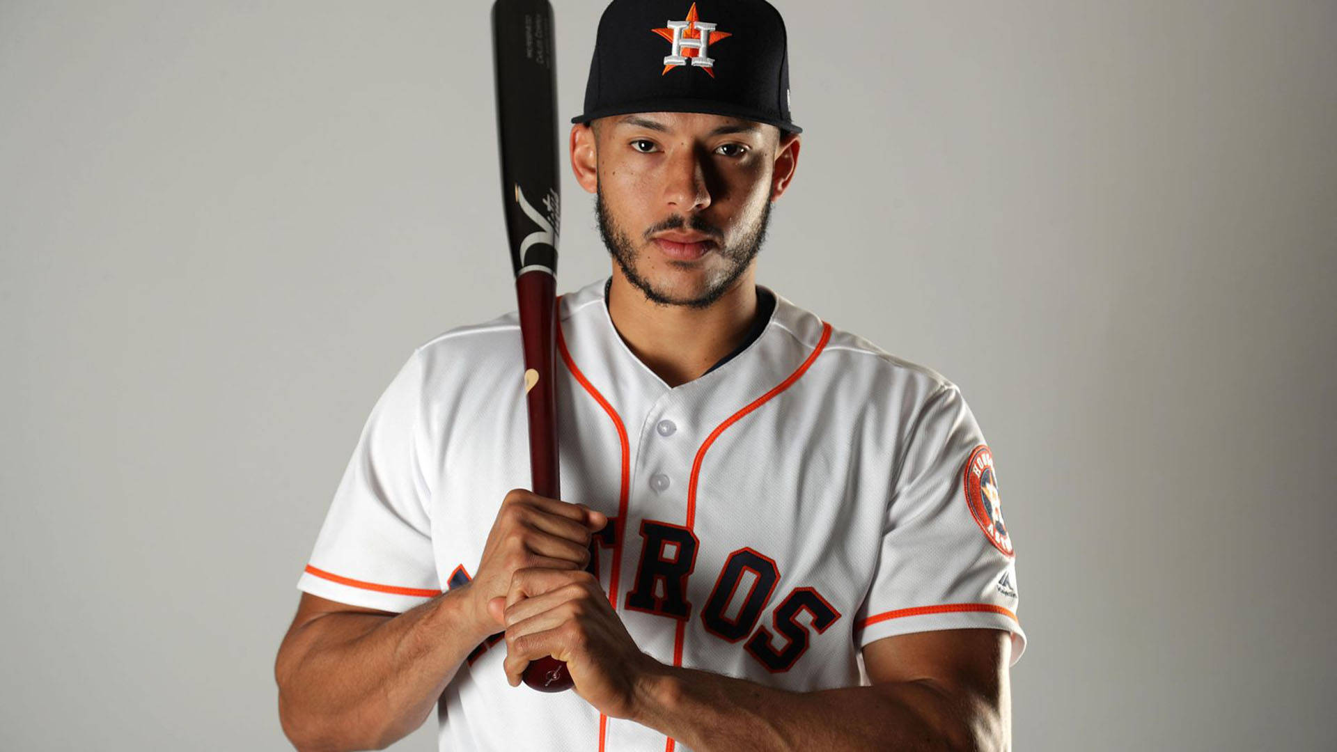 Carlos Correa 桌布 壁紙 — 一名身穿休士頓太空人隊球衣的棒球運動員，在純灰色背景下專注地握著球棒。