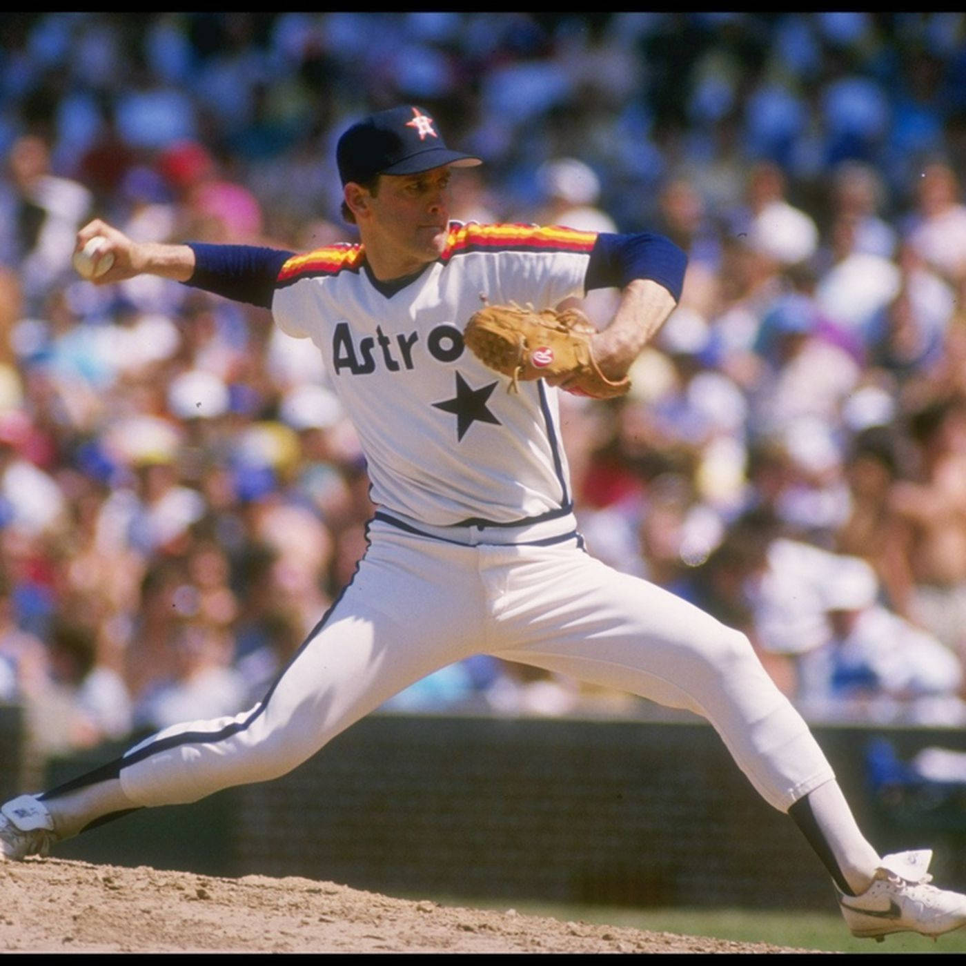 Nolan Ryan 桌布 壁紙 — 一名身穿休士頓太空人隊球衣的棒球投手在陽光普照的投手丘上投球，背景是模糊的人群。