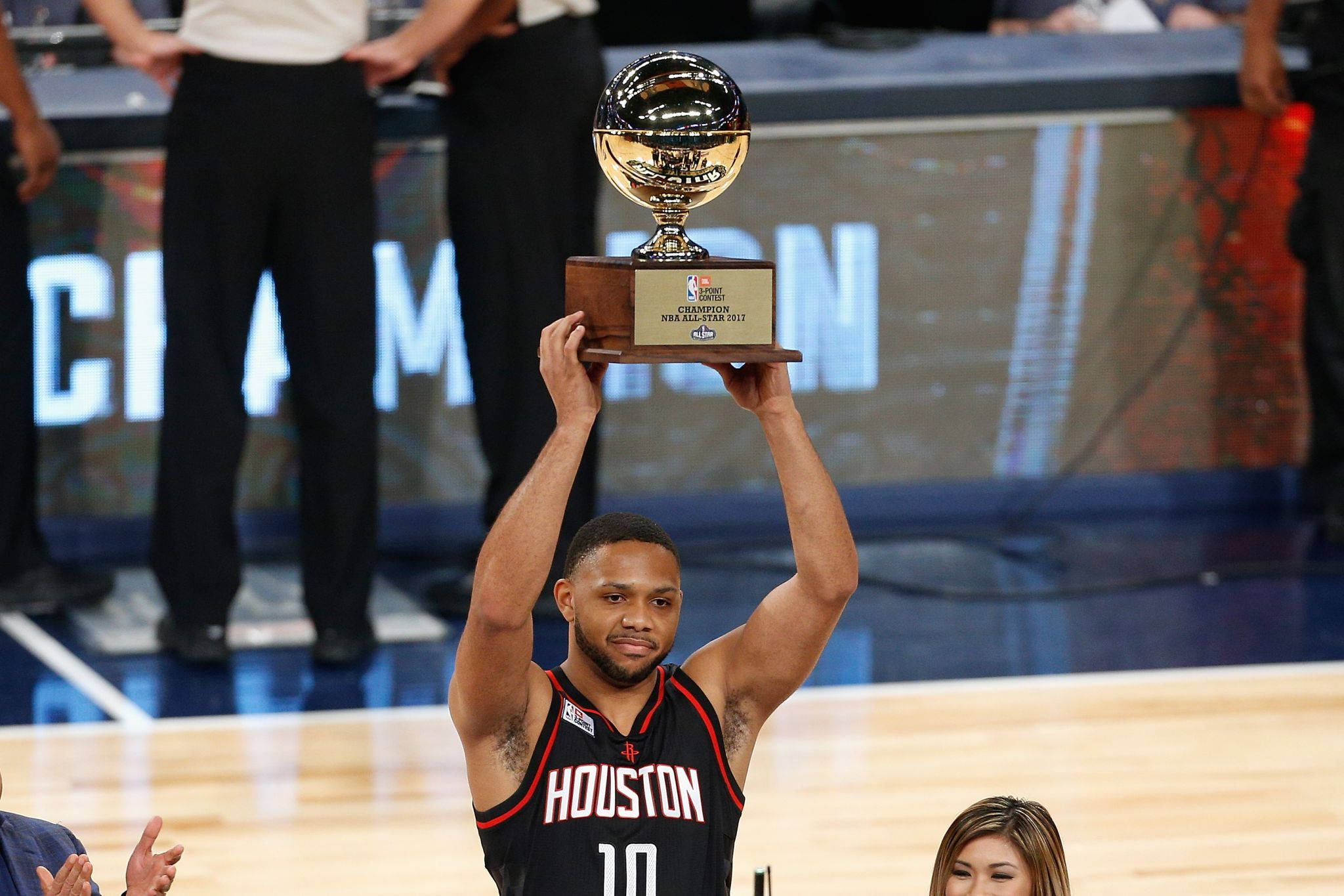 eric gordon 桌布 壁紙 — 一名身穿休士頓球衣的籃球運動員在球場上高舉NBA總冠軍獎盃，慶祝勝利。