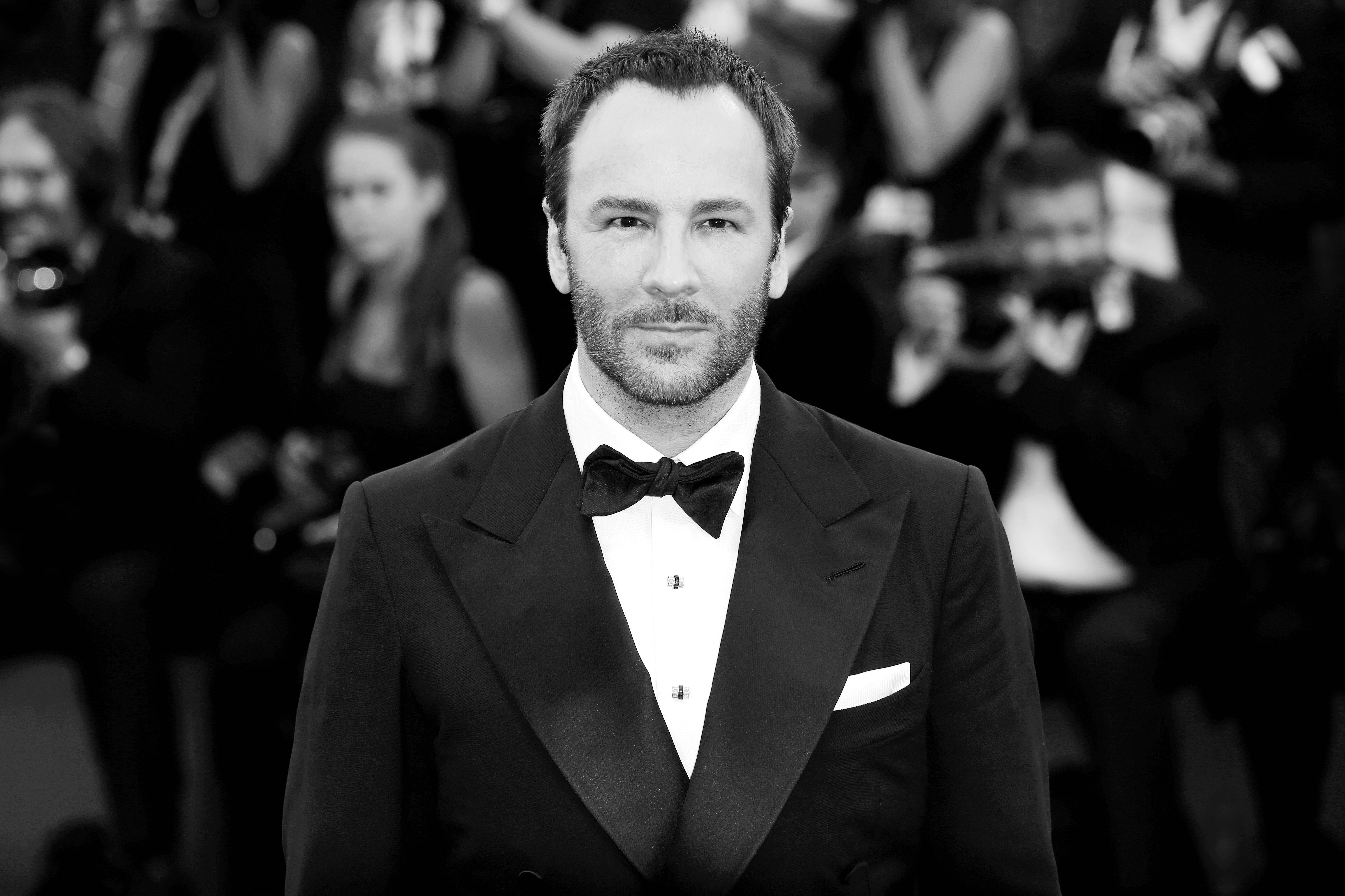 Celebrity 桌布 壁紙 — 一名身穿俐落黑色燕尾服配蝴蝶結的男子自信地站在紅地毯上，身後攝影師閃光燈不斷。