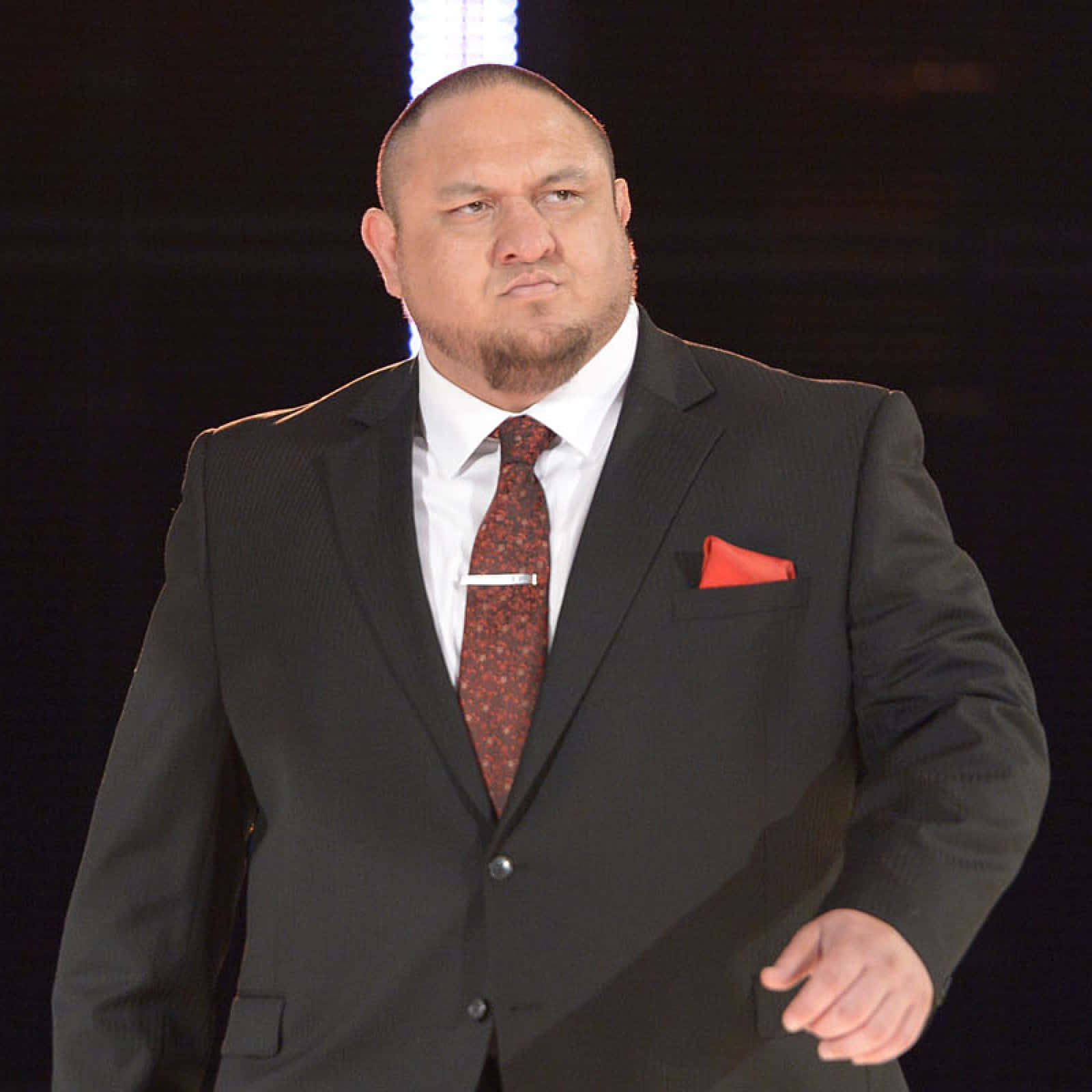 WWE 桌布 壁紙 — 一名身穿俐落黑色西裝、搭配紅色圖案領帶和相配袋巾的男子，在深色背景下自信地站立。