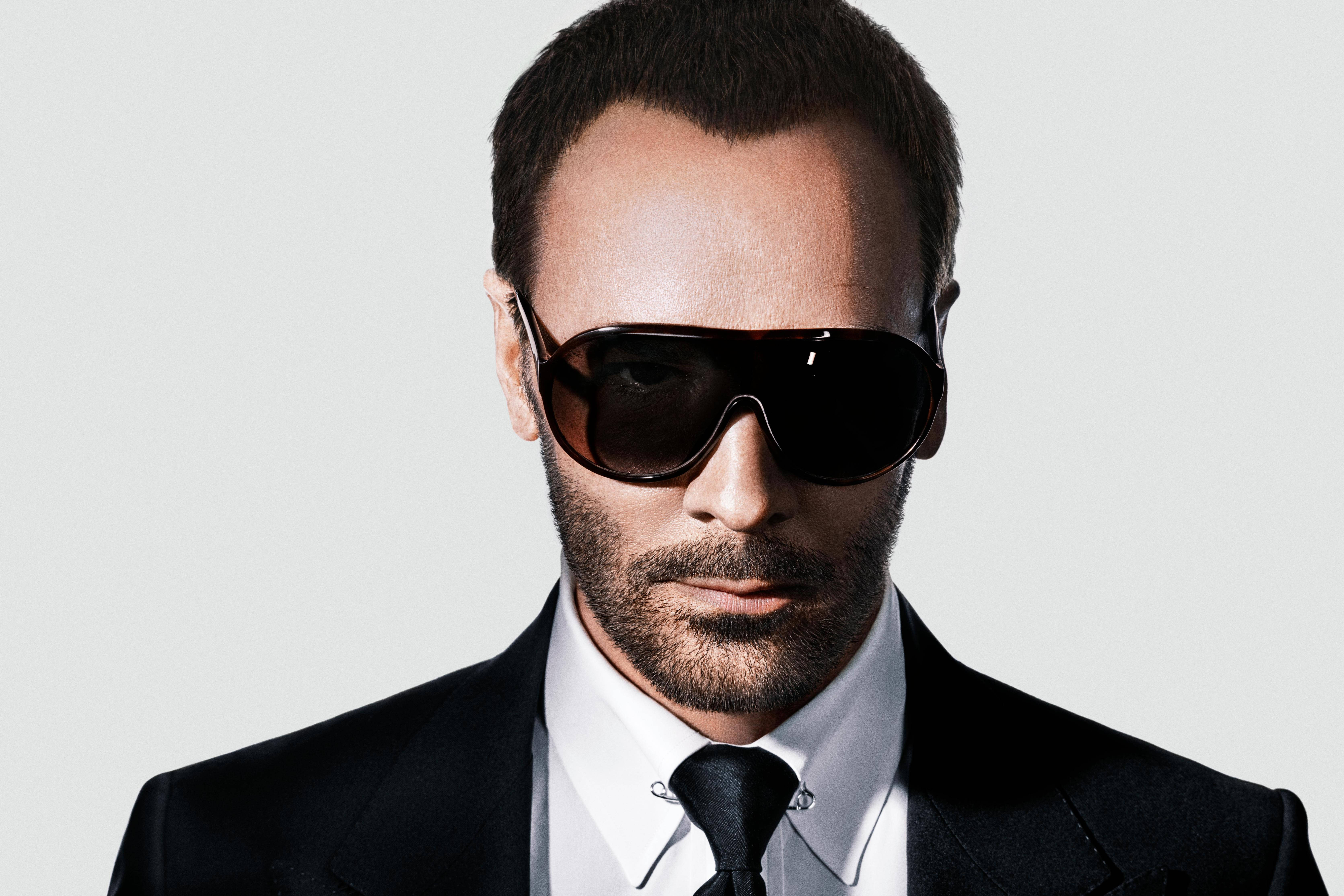 Sunglasses 桌布 壁紙 — 一名身穿俐落黑色西裝和白色襯衫的男子，在純淺灰色背景前戴著超大的深色太陽眼鏡。