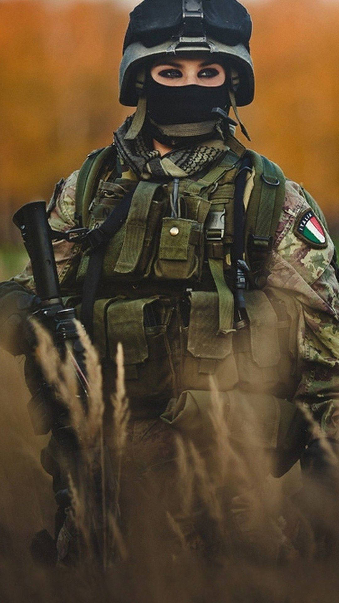一名身穿迷彩裝備的士兵在秋季的高草叢中手持步槍。 — 軍隊 壁紙