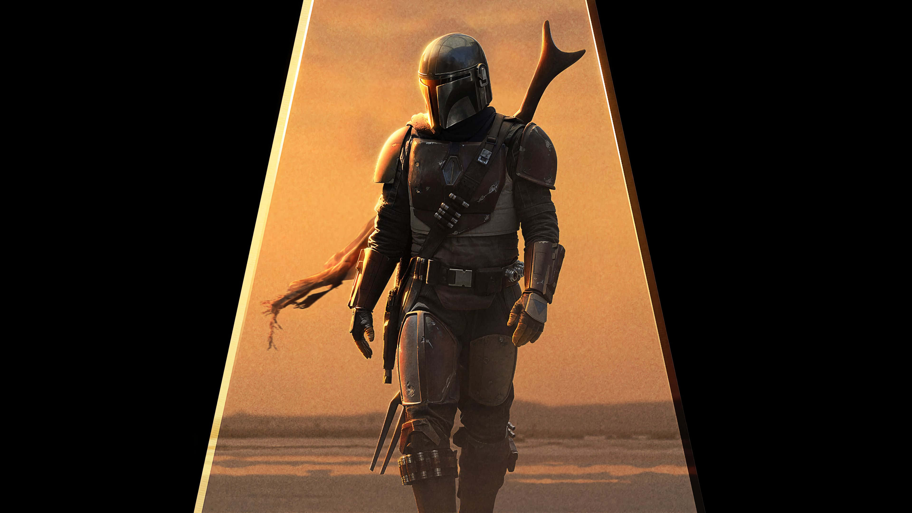 Mandalorian Pc 桌布 壁紙 — 一名身穿全套盔甲的曼達洛戰士在日落時分穿越沙漠，肩上掛著一把爆能槍。