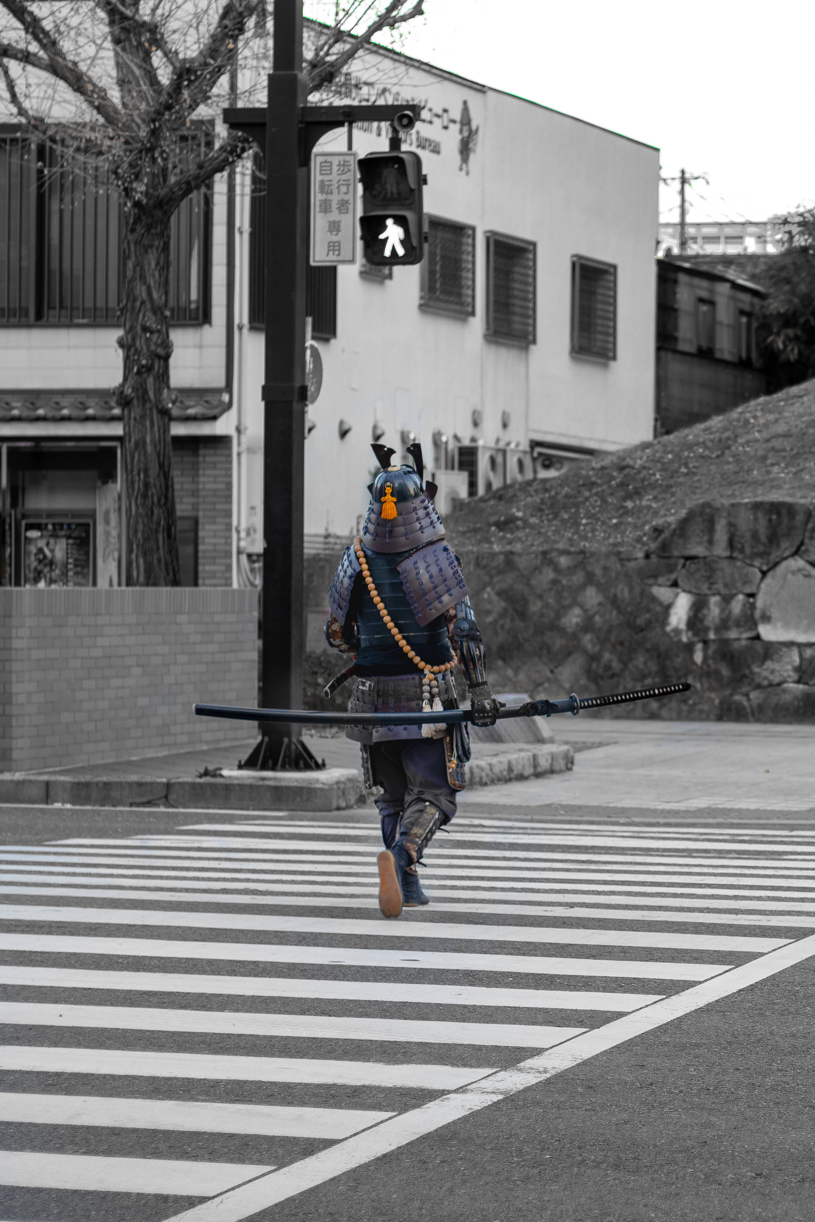 武士動畫 桌布 壁紙 — 一名身穿全套盔甲的武士在日本城市環境中，在行人號誌燈下走過現代化的行人穿越道。