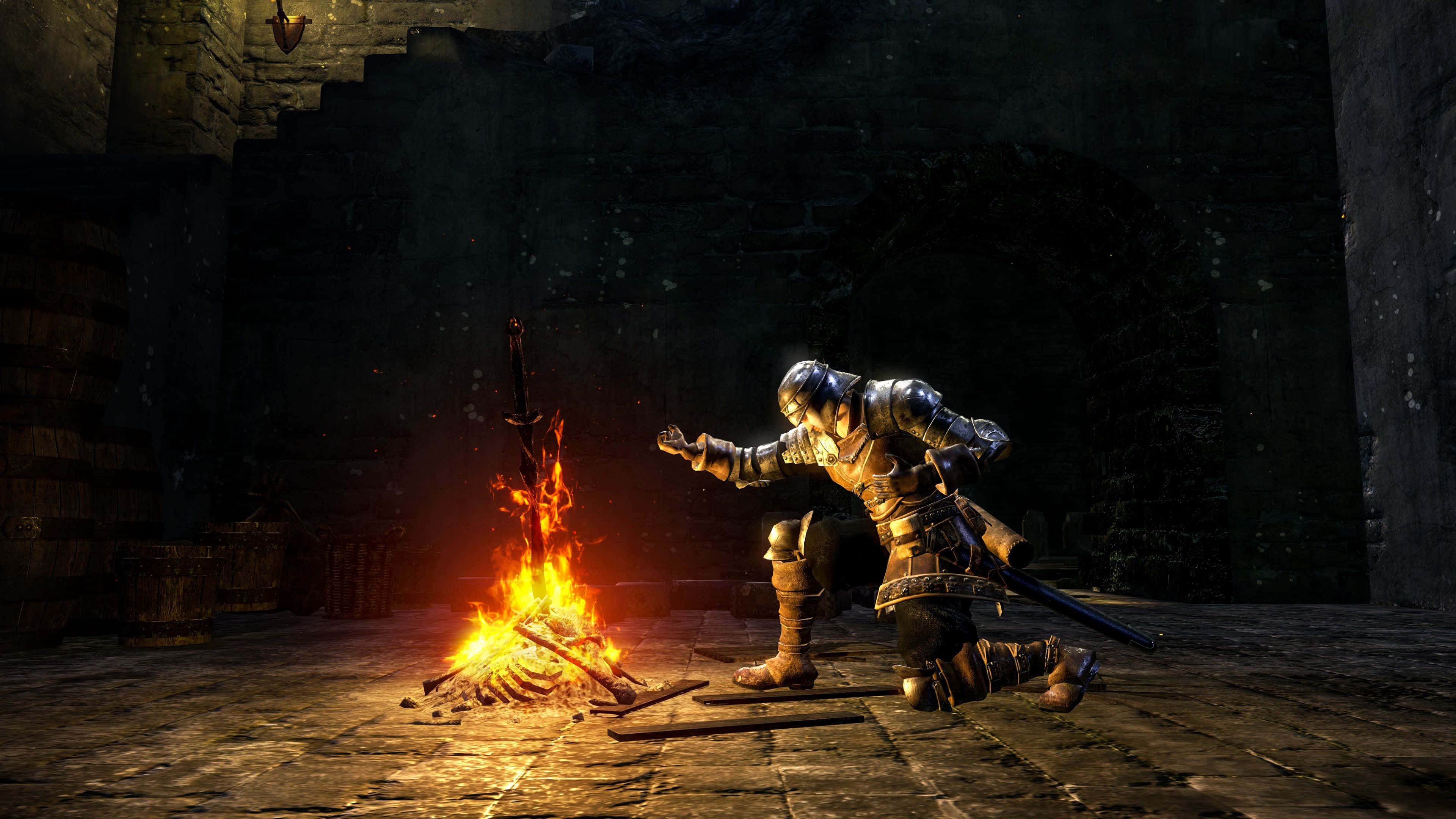 Dark Souls Bonfire 桌布 壁紙 — 一名身穿全套盔甲的騎士在昏暗的石頭地牢中跪在熊熊營火旁，溫暖的光芒映照在古老的牆壁和木桶上。