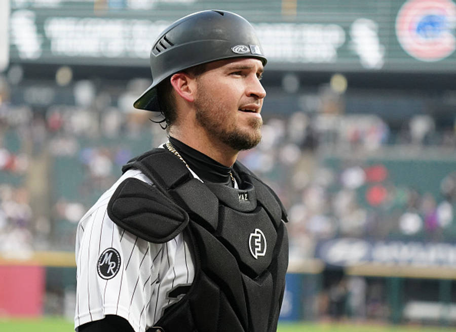 MLB 桌布 壁紙 — 一名身穿全套裝備的棒球捕手專注地站在球場上，背景是體育館的人群和記分板。