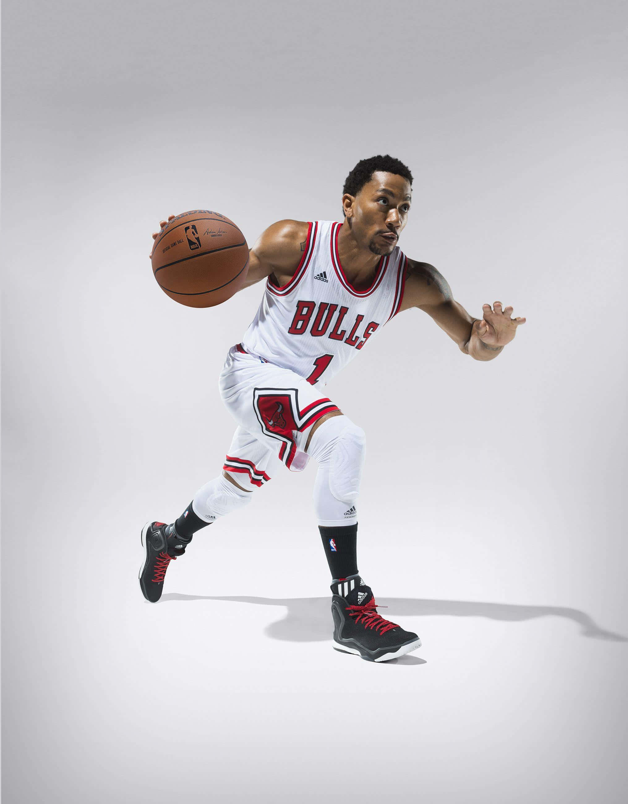 derrick rose 桌布 壁紙 — 一名身穿公牛隊球衣的籃球運動員在純灰色工作室背景前跨步運球。