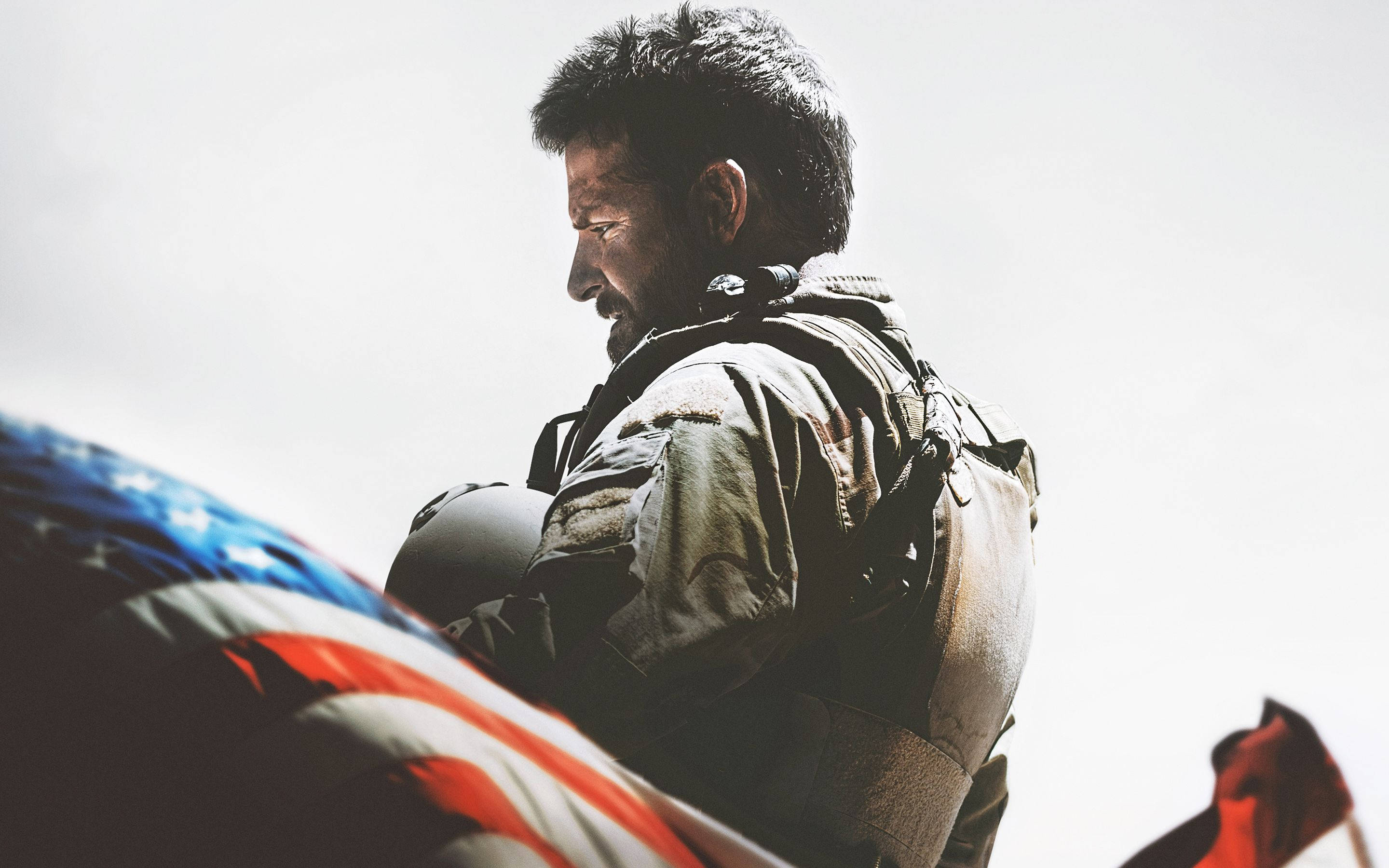 American 桌布 壁紙 — 一名身穿制服、神情肅穆的士兵在明亮的天空下舉著美國國旗，臉上刻劃著靜默的敬意。